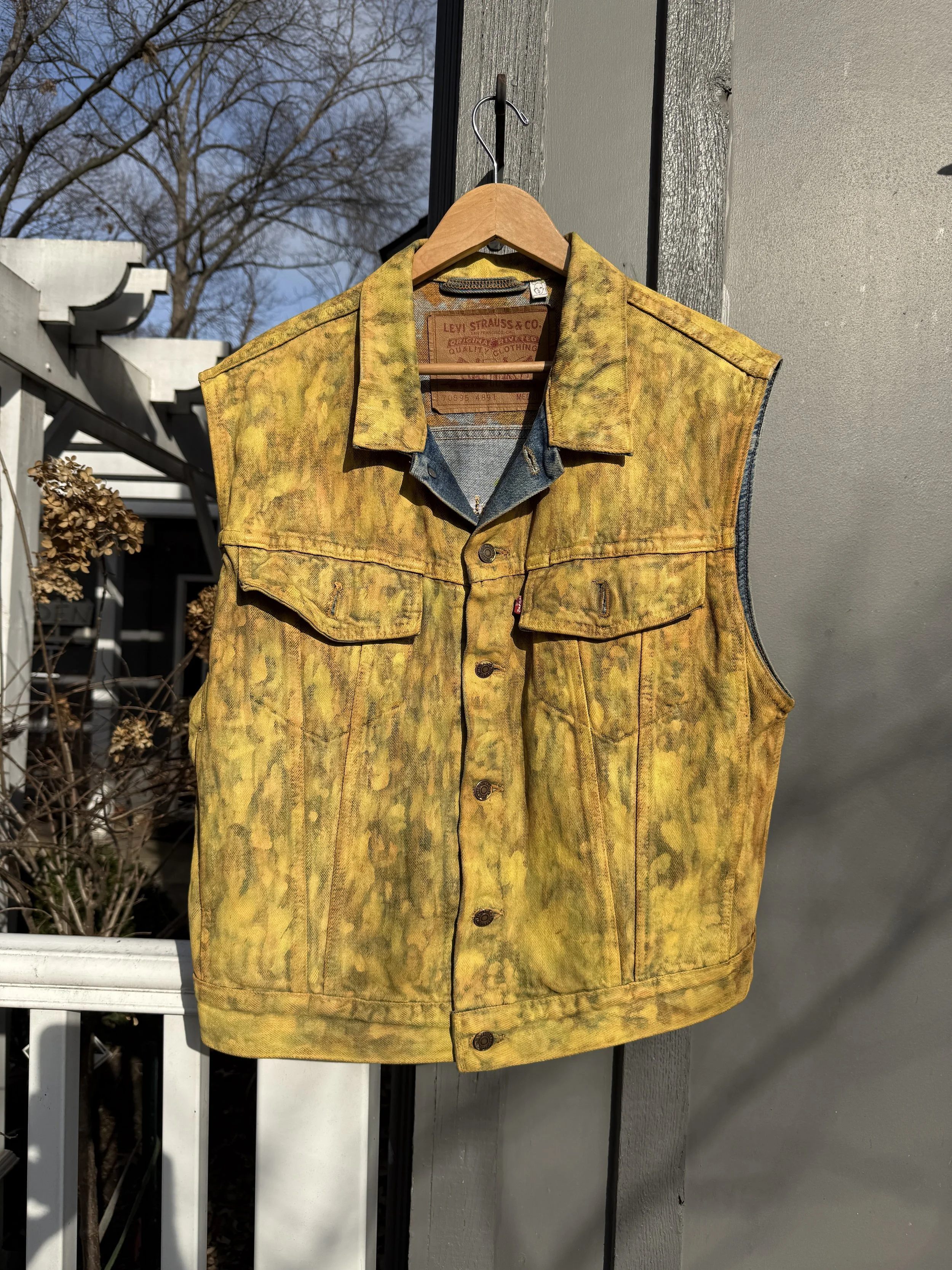 Front view of a distressed yellow sleeveless denim vest with a mottled, hand-worked surface.