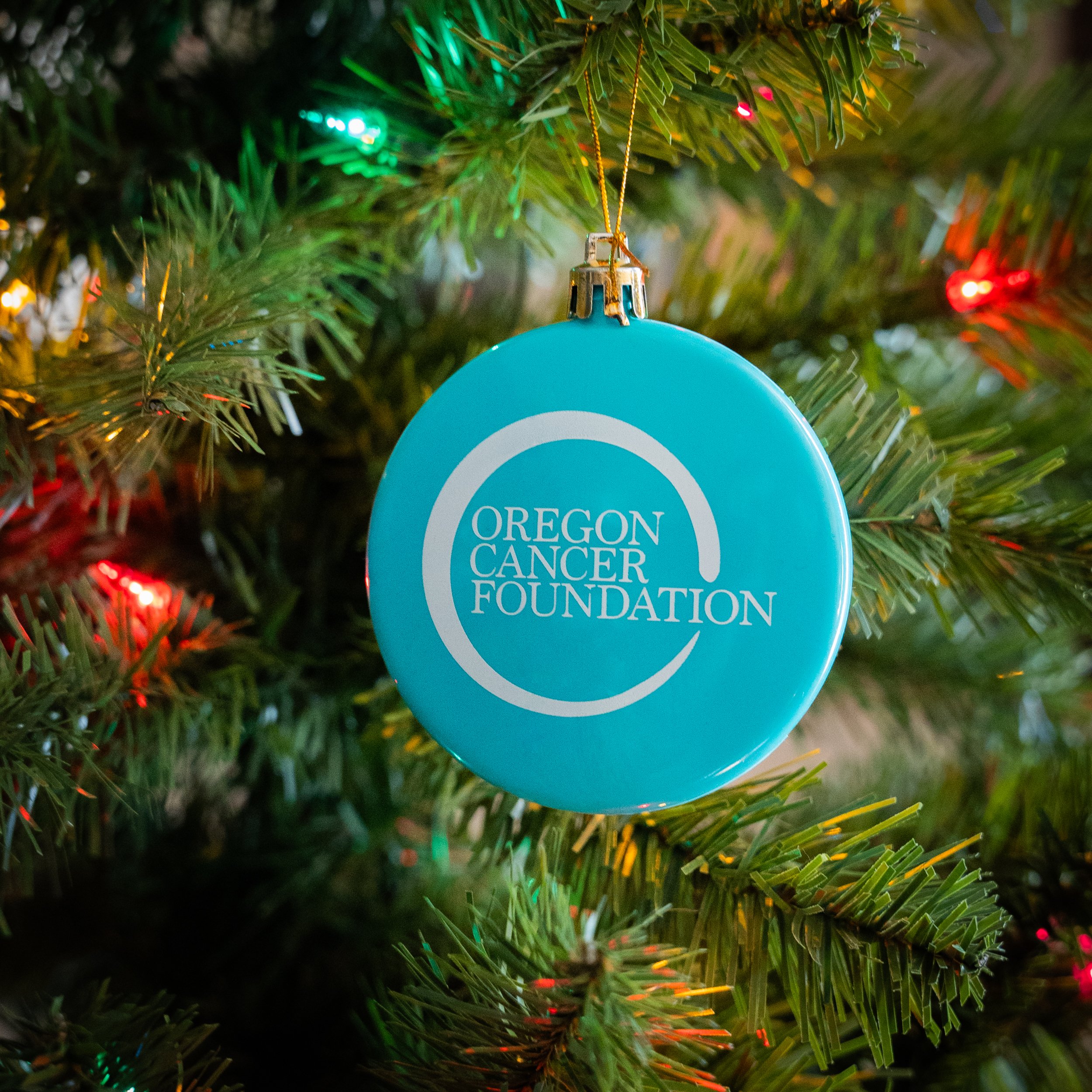 A blue round ornament with the Oregon Cancer Foundation logo printed in white