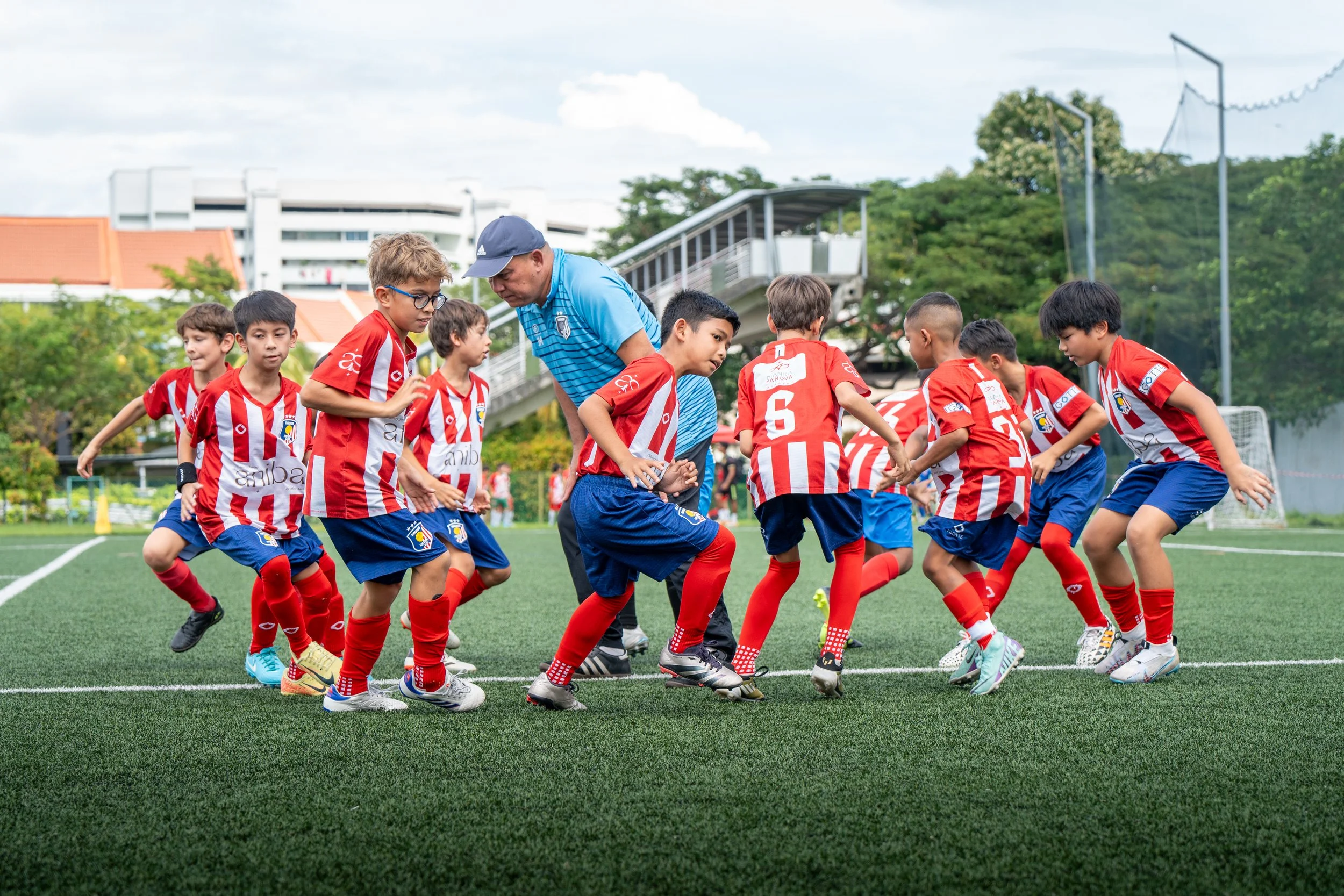 EuroAsia FC coach explaining European football tactics to youth players at training in Singapore