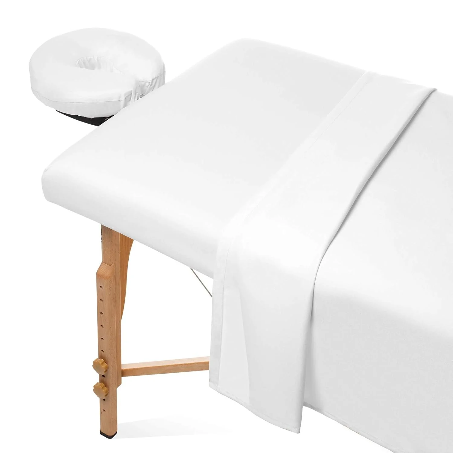 A massage table covered with a white sheet and a pillow, with a mounted adjustable wooden leg underneath.