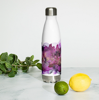 A white thermos with purple flowers design next to a green lime, a yellow lemon, and a sprig of mint on a white surface.
