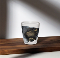 A glass with dark liquid and floating popping boba on a wooden surface.