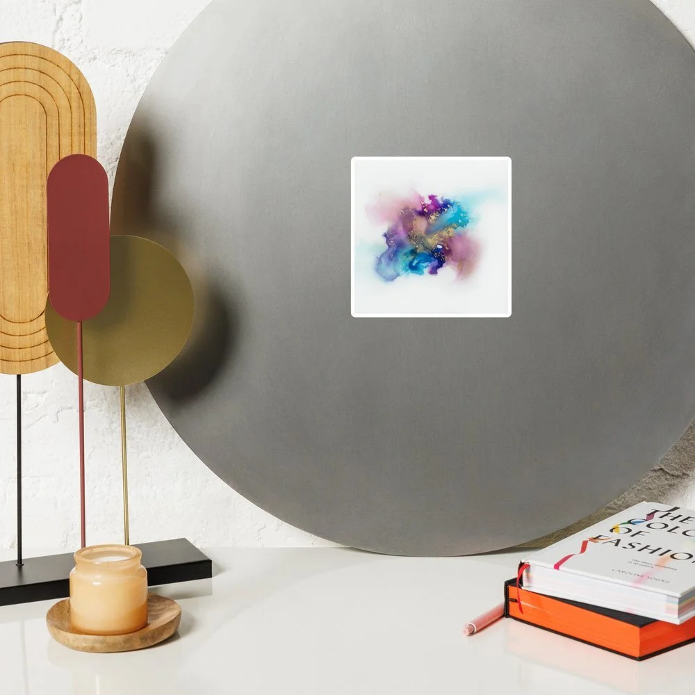 Decorative room with geometric wall art, a small candle, and a fashion book on a white table.