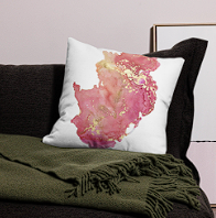Decorative pillow with a pink watercolor map design, placed on a sofa with a green throw blanket.