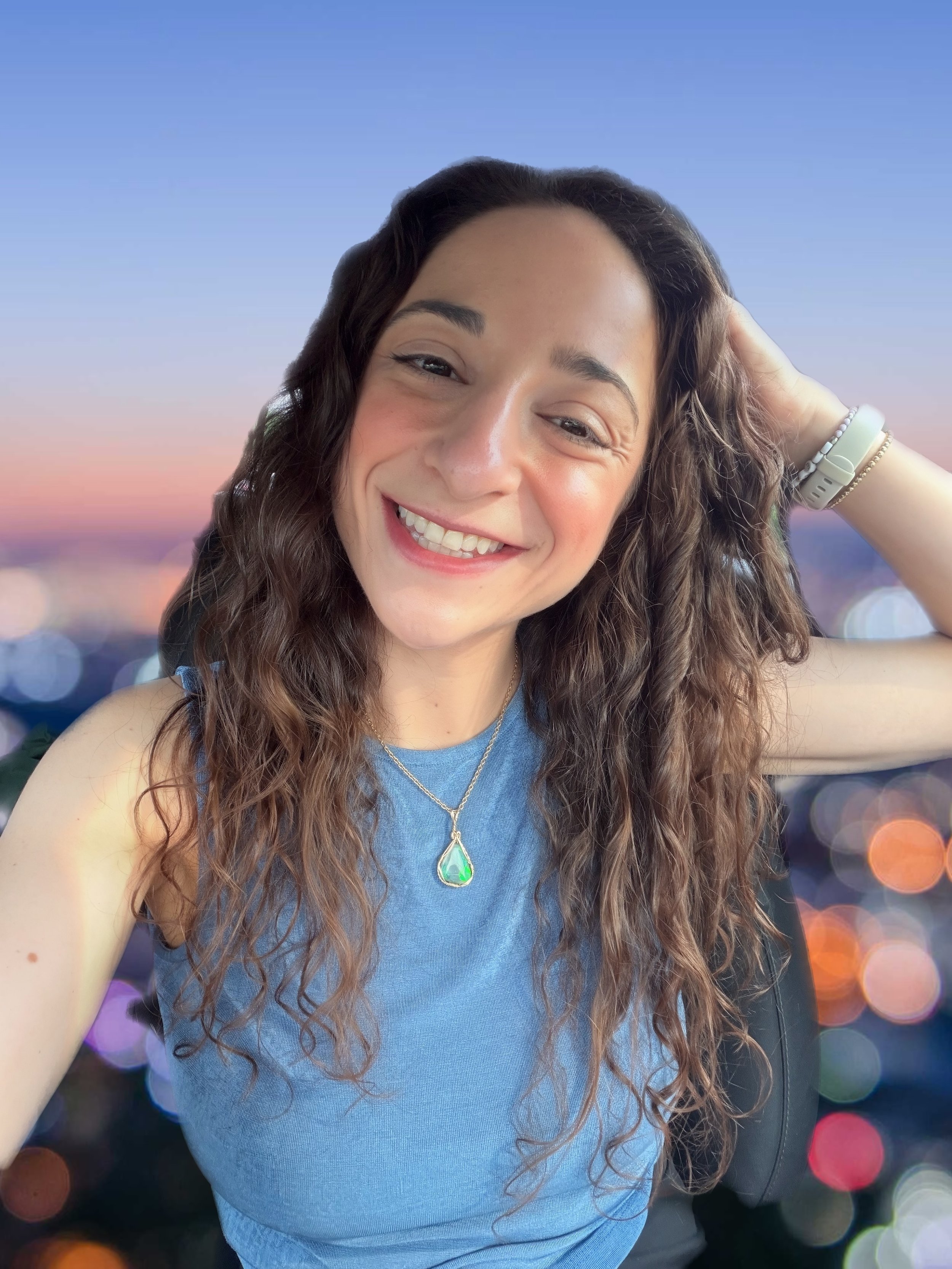 Image of woman smiling at the camera in a royal blue tank top with blue gemstone necklace