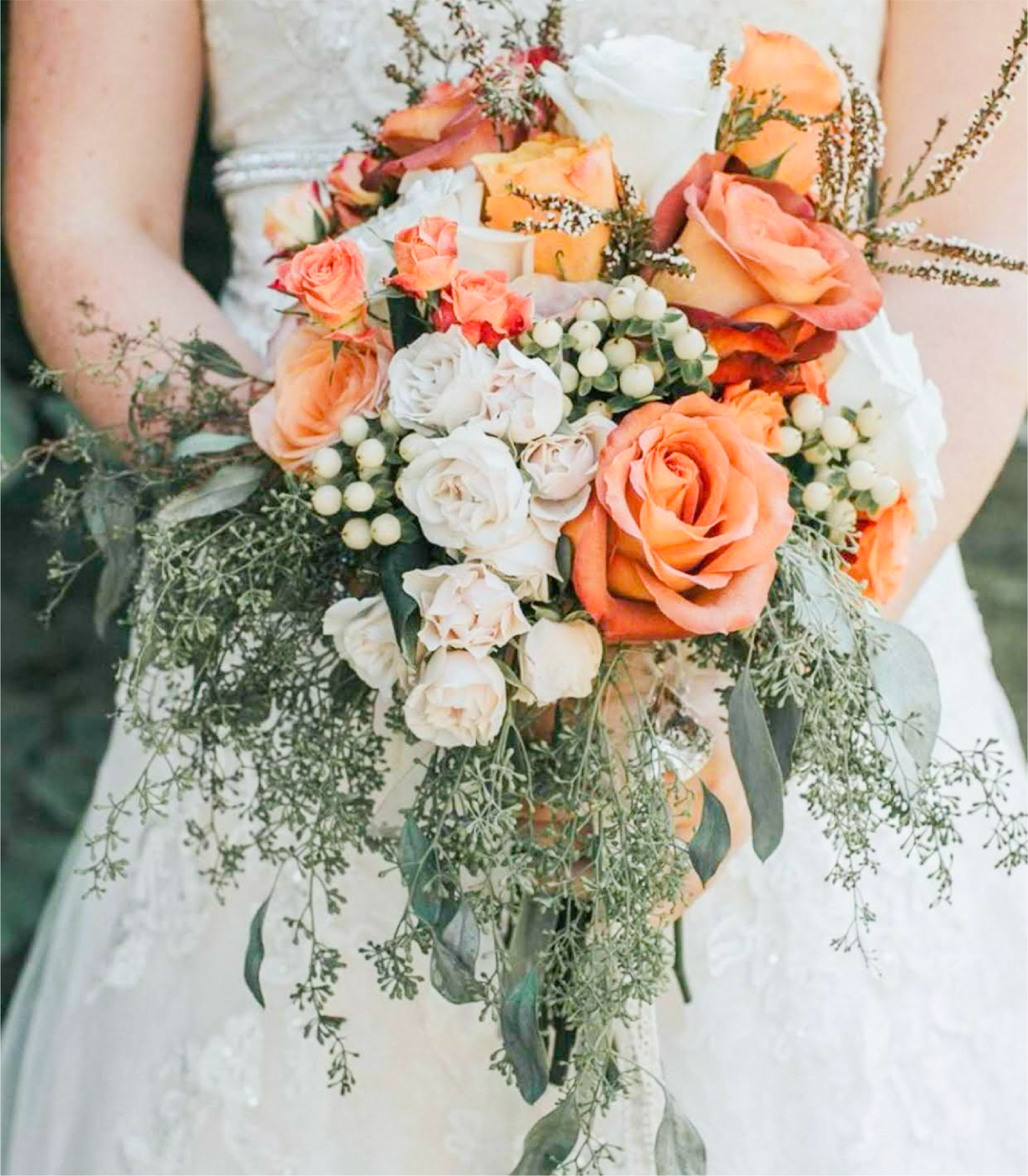 Bridal bouquet with orange and white roses and greenery.