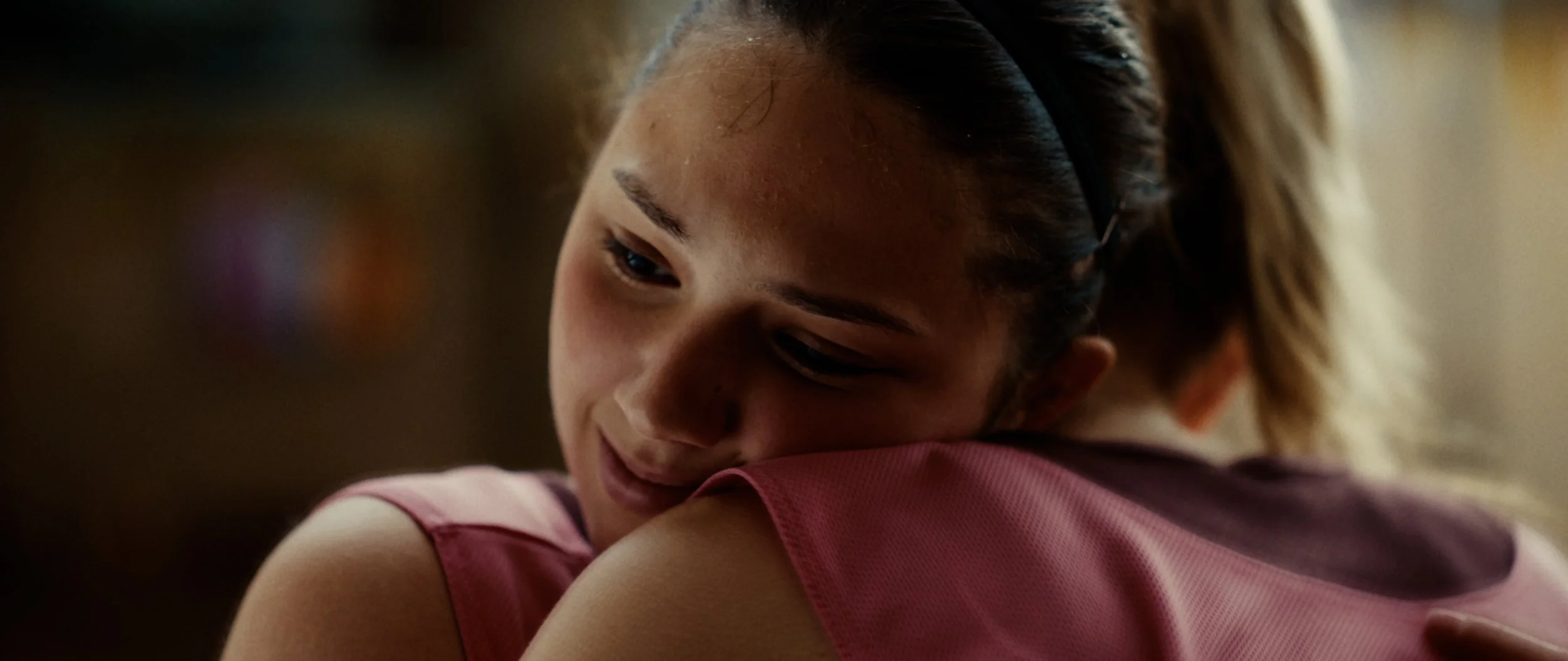 A young girl hugging someone, with a gentle smile on her face.