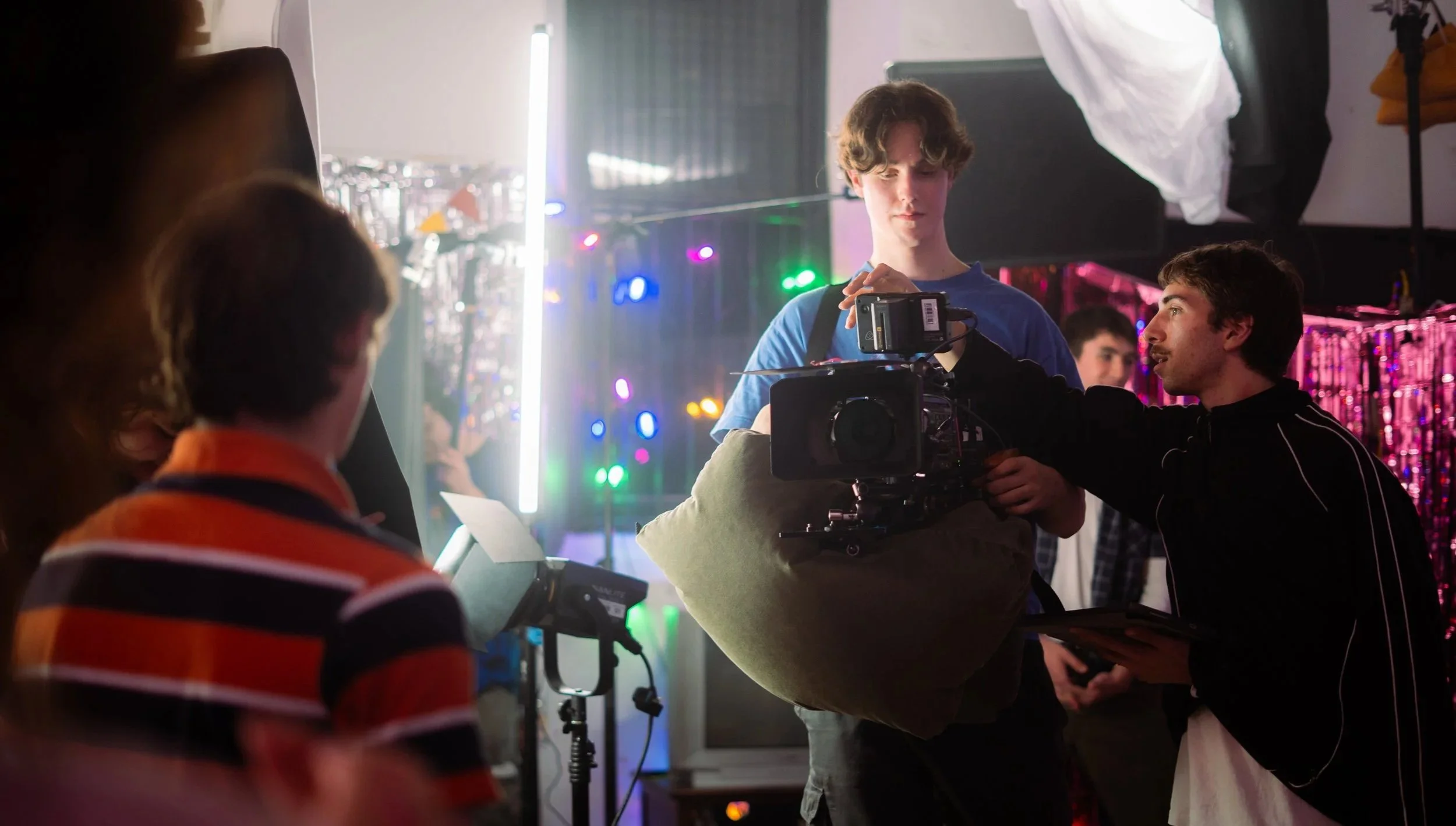 Group of people filming in a colorful, vibrant setting with bright lights and decorations.