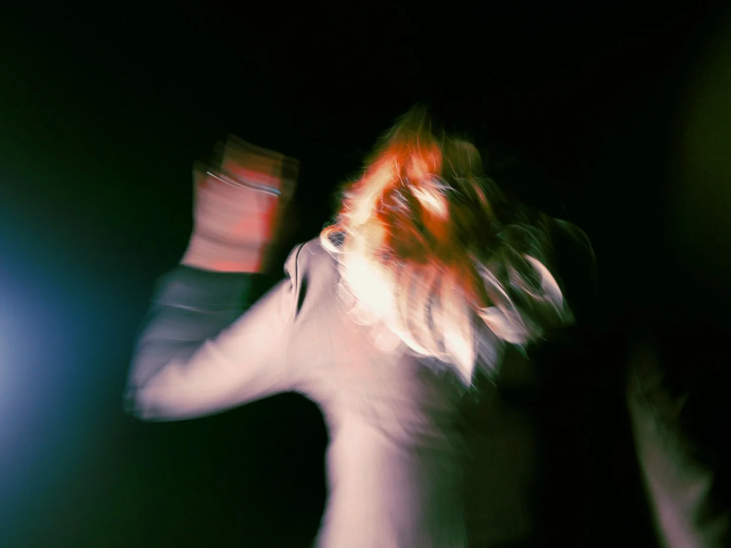 Blurry person with red hair against dark background, motion effect.
