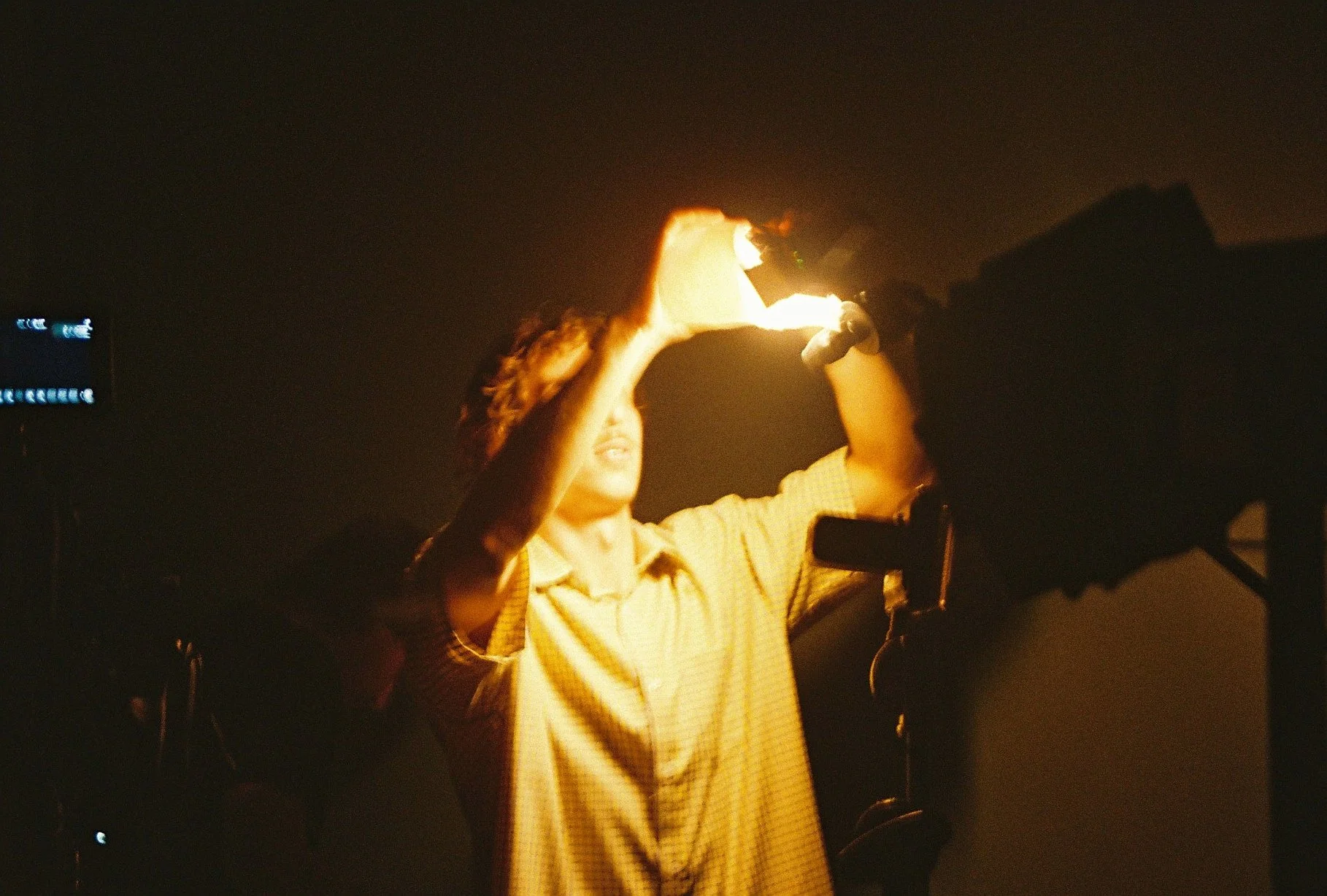 A person holding a fire torch in front of a camera in a dark setting.