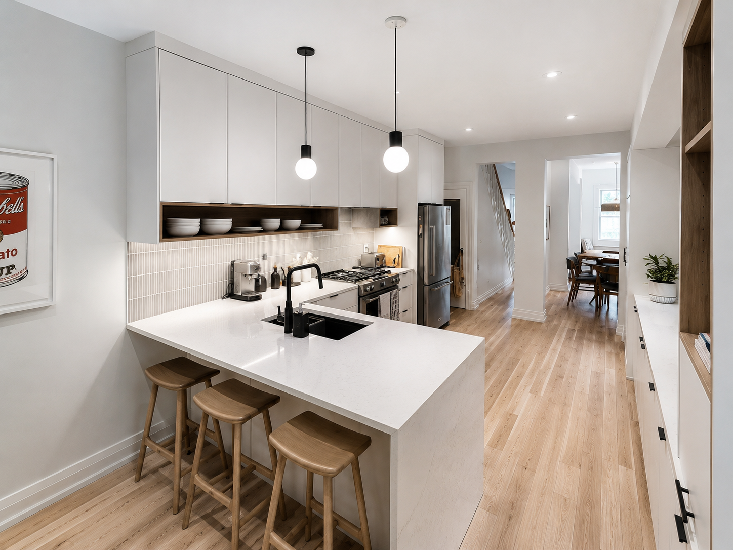Modern kitchen with white cabinets, light wood flooring, a white island with a black sink and faucet, three wooden stools, stainless steel appliances, open shelving with bowls, and pendant lights.