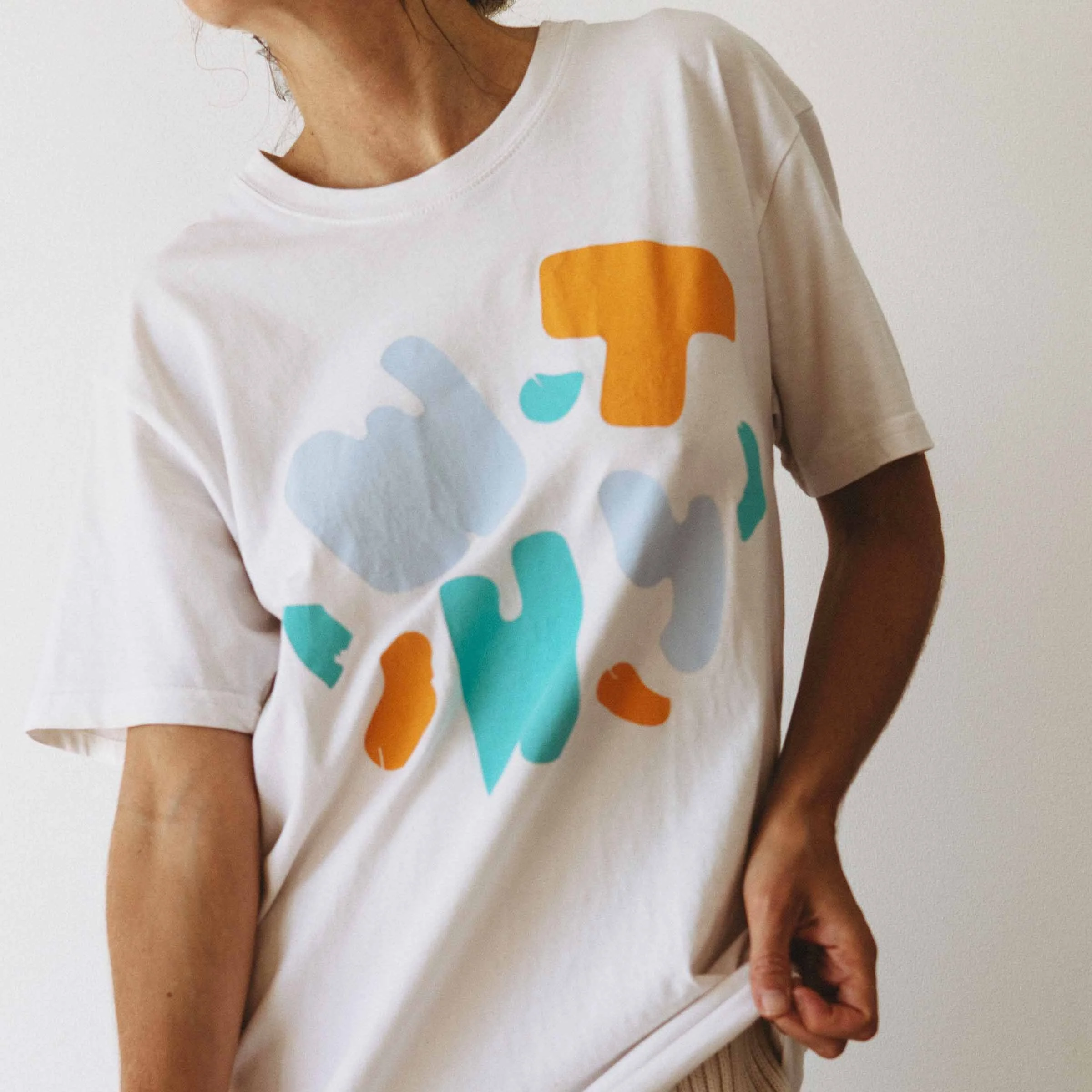 A woman in a white oversized t-shirt, featuring a colourful WTHY graphic.