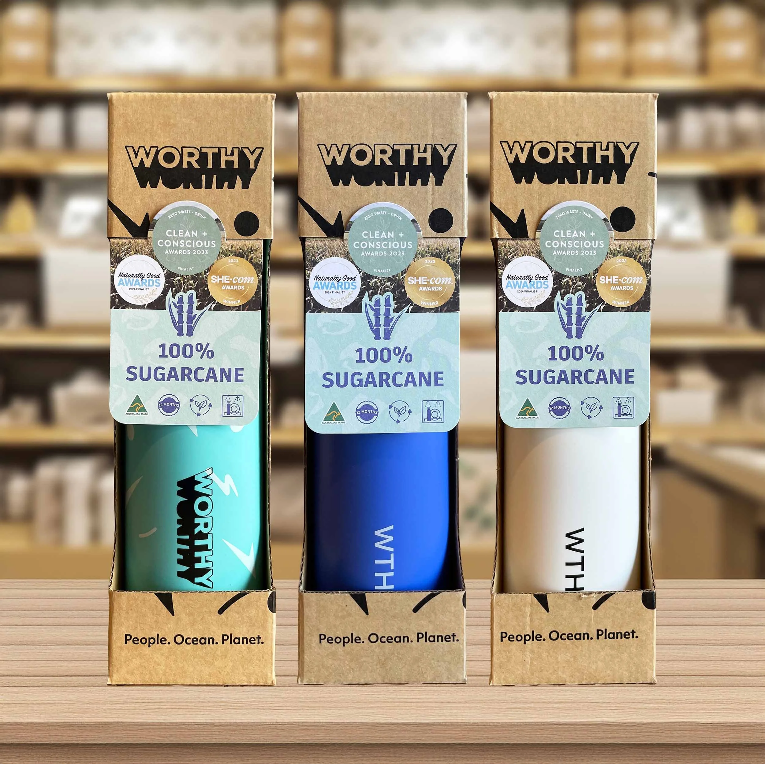 3 Worthy drink bottles, packaged in their boxes, with a bottle-neck label attached.
