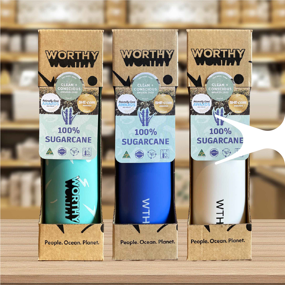 A set of 3 Worthy drink bottles with bottle neck labels and packaged in boxes, sitting on a store shelf.
