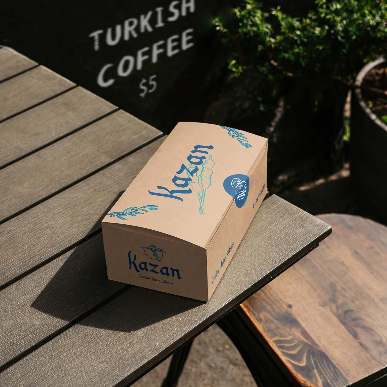 A brown takeaway food box stamped with the Kazan branding.