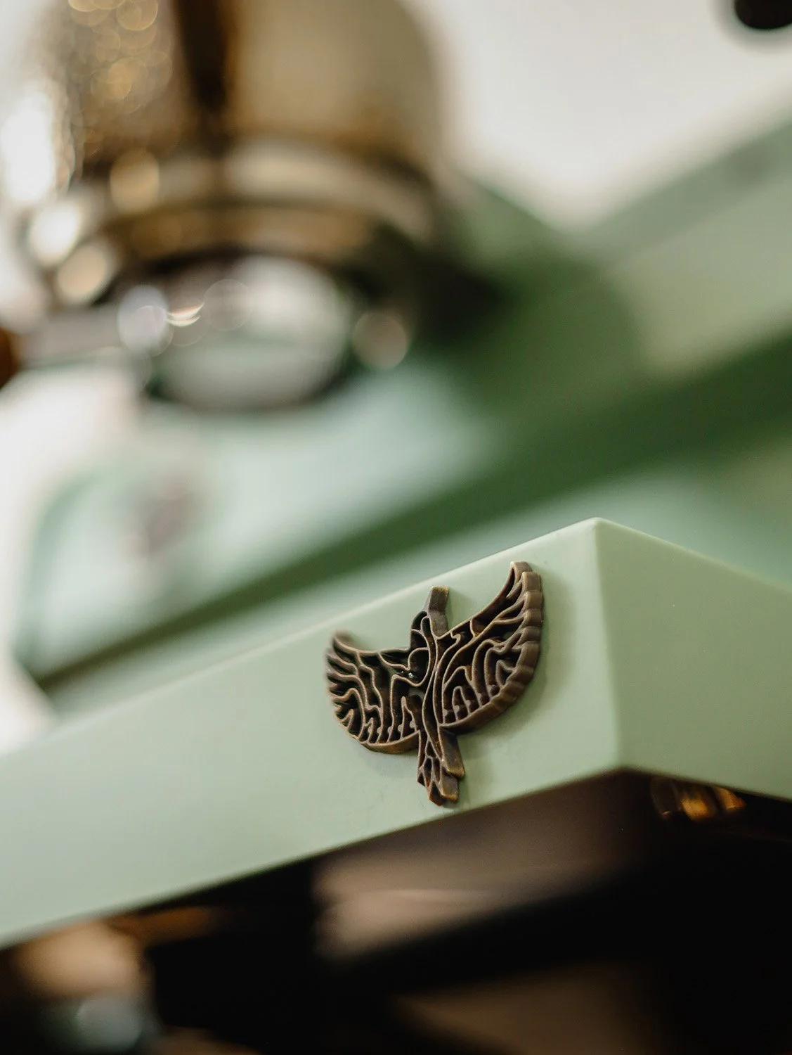 Specht woodpecker icon in timber, applied on a green Slayer espresso machine.