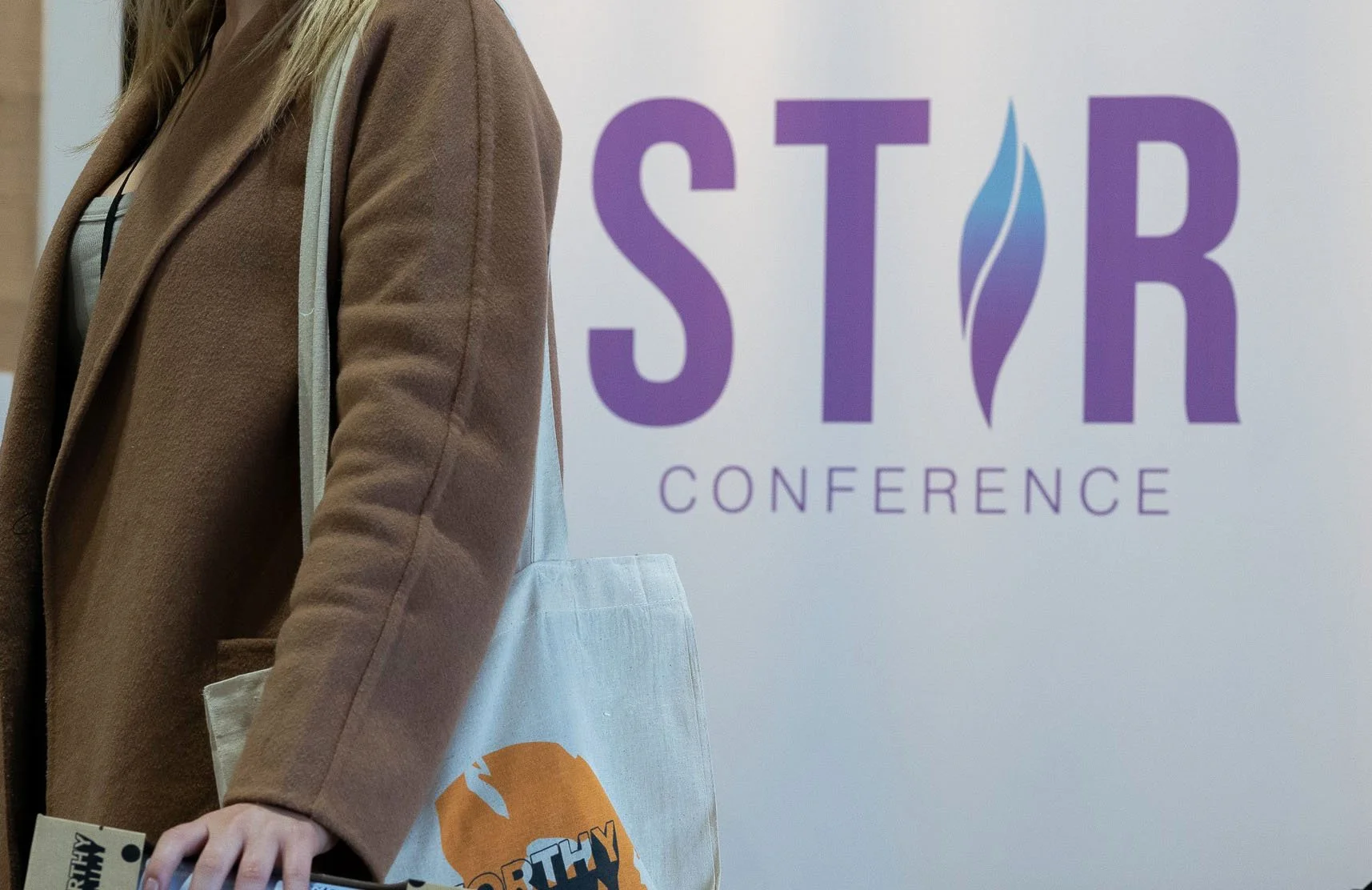 A close-up shot of a white pull-up banner, featuring the STIR Conference logo.