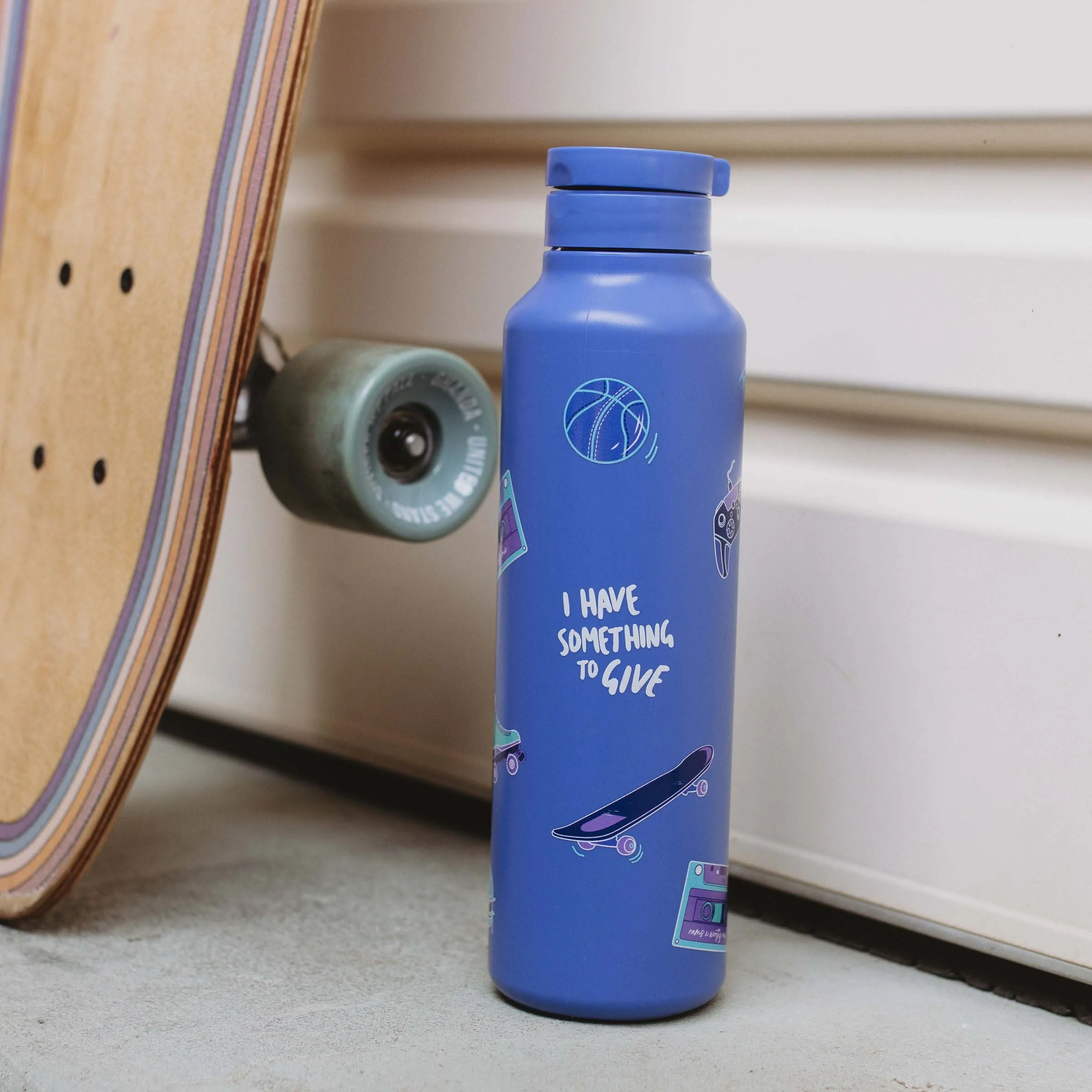A blue Worthy bottle sits beside a skateboard.