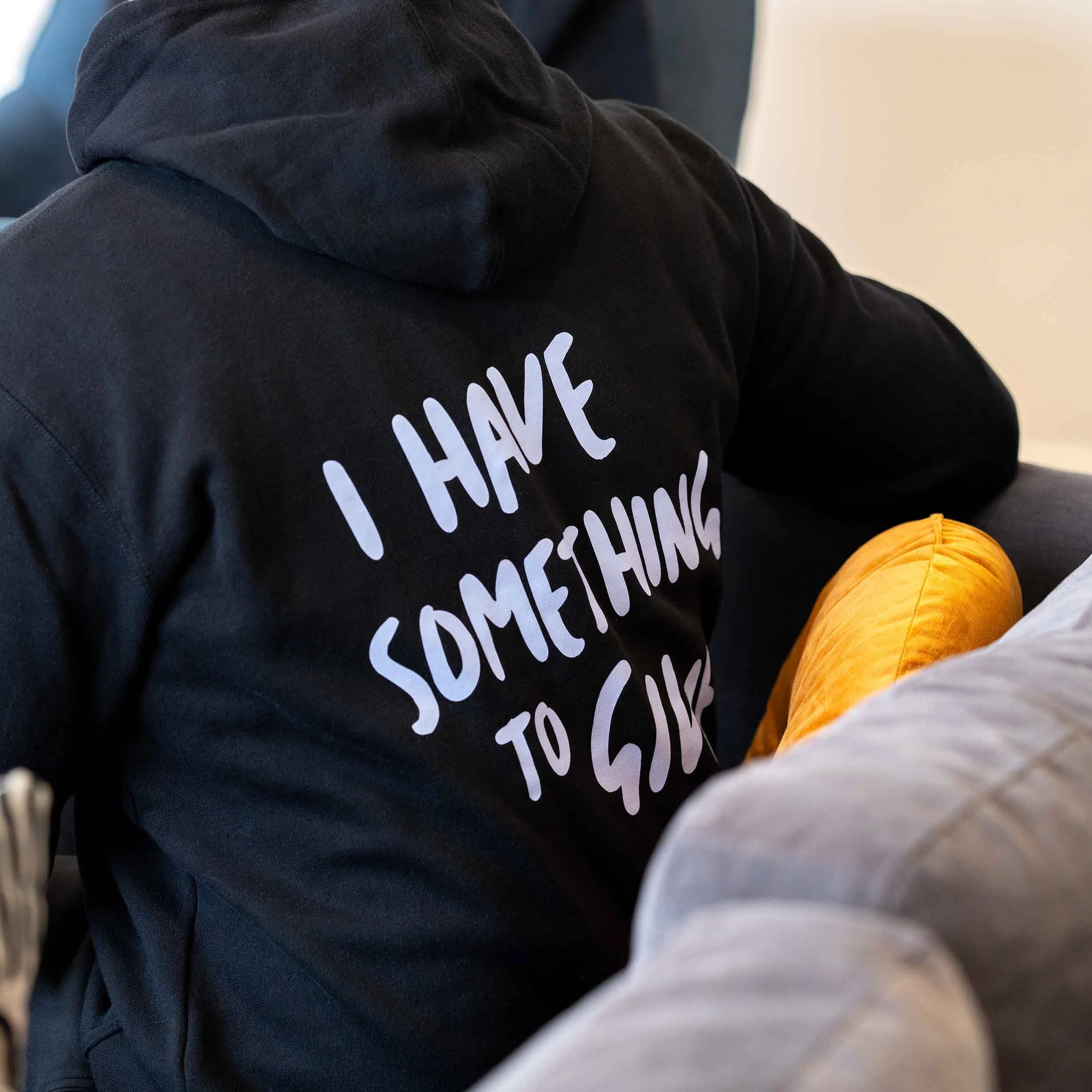 A back view of a man wearing a black RAMS hoodie with the quote "I have something to give" on it.