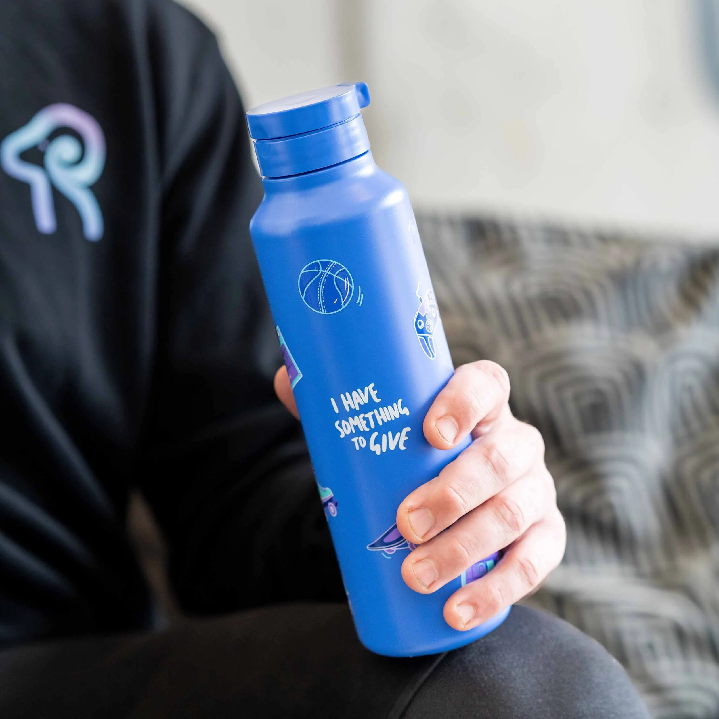 A close up photograph of a man holding a blue RAMS drink bottle.