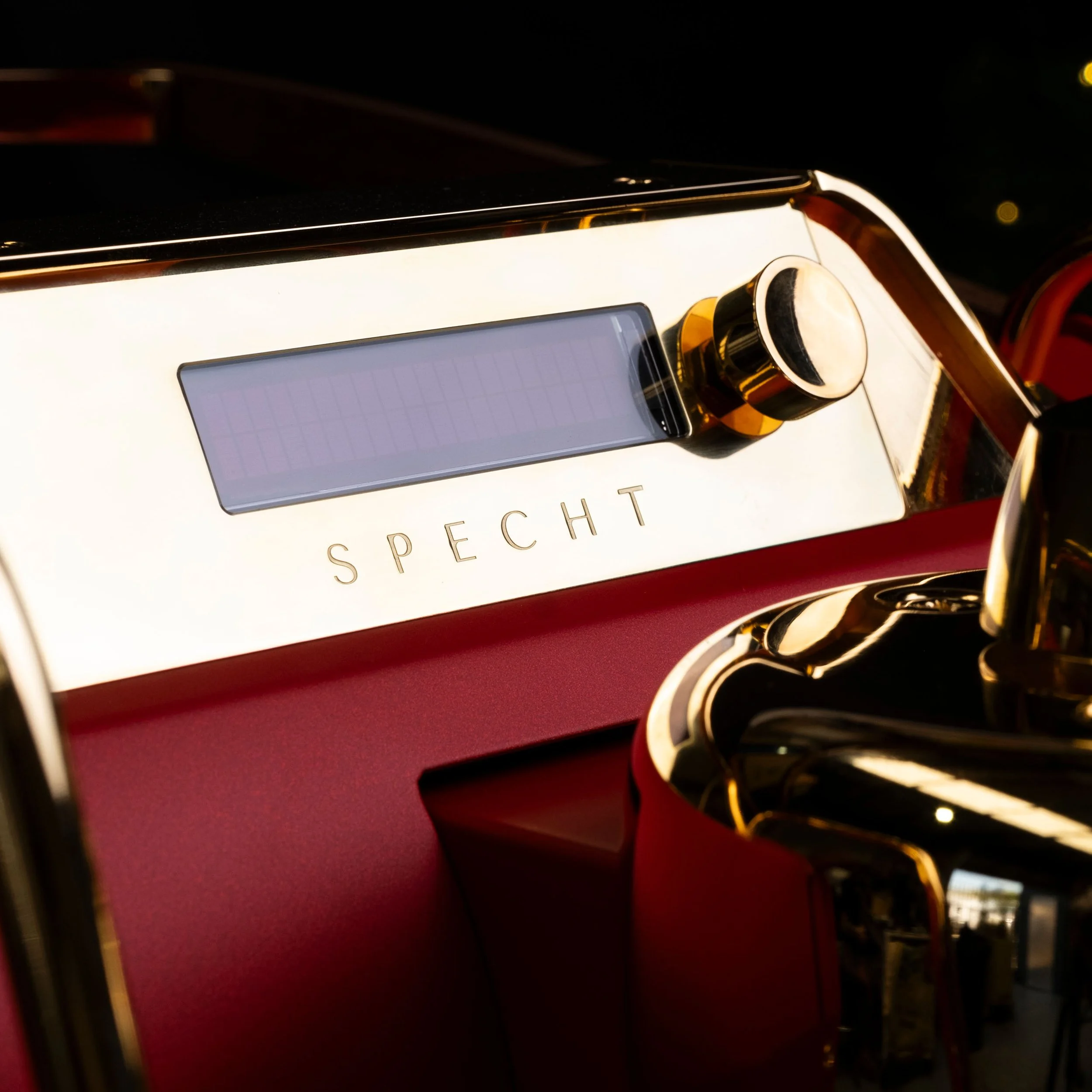 A red Slayer espresso machine by Specht, featuring their logo in etched gold.