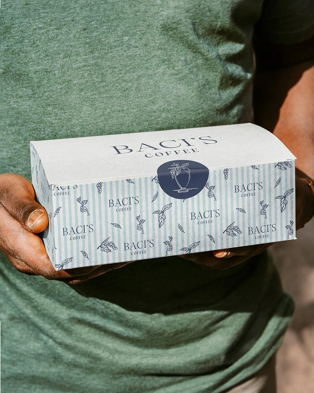 Branded cardboard food packaging for Baci's Coffee, held in a man's hands.