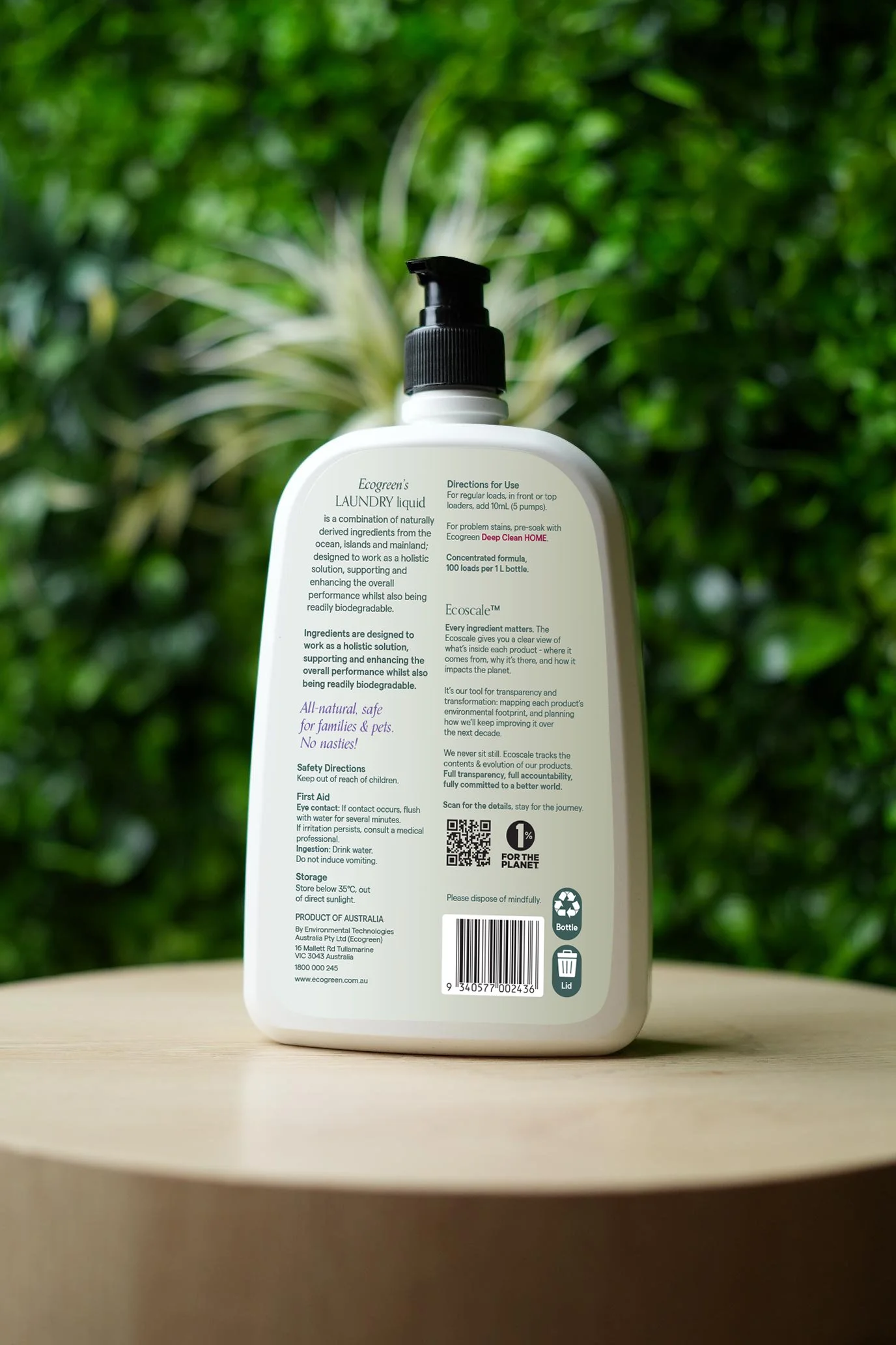 Bottle of Ecogreen laundry liquid, sitting on a wooden stand with greenery in the background, the back label in view.