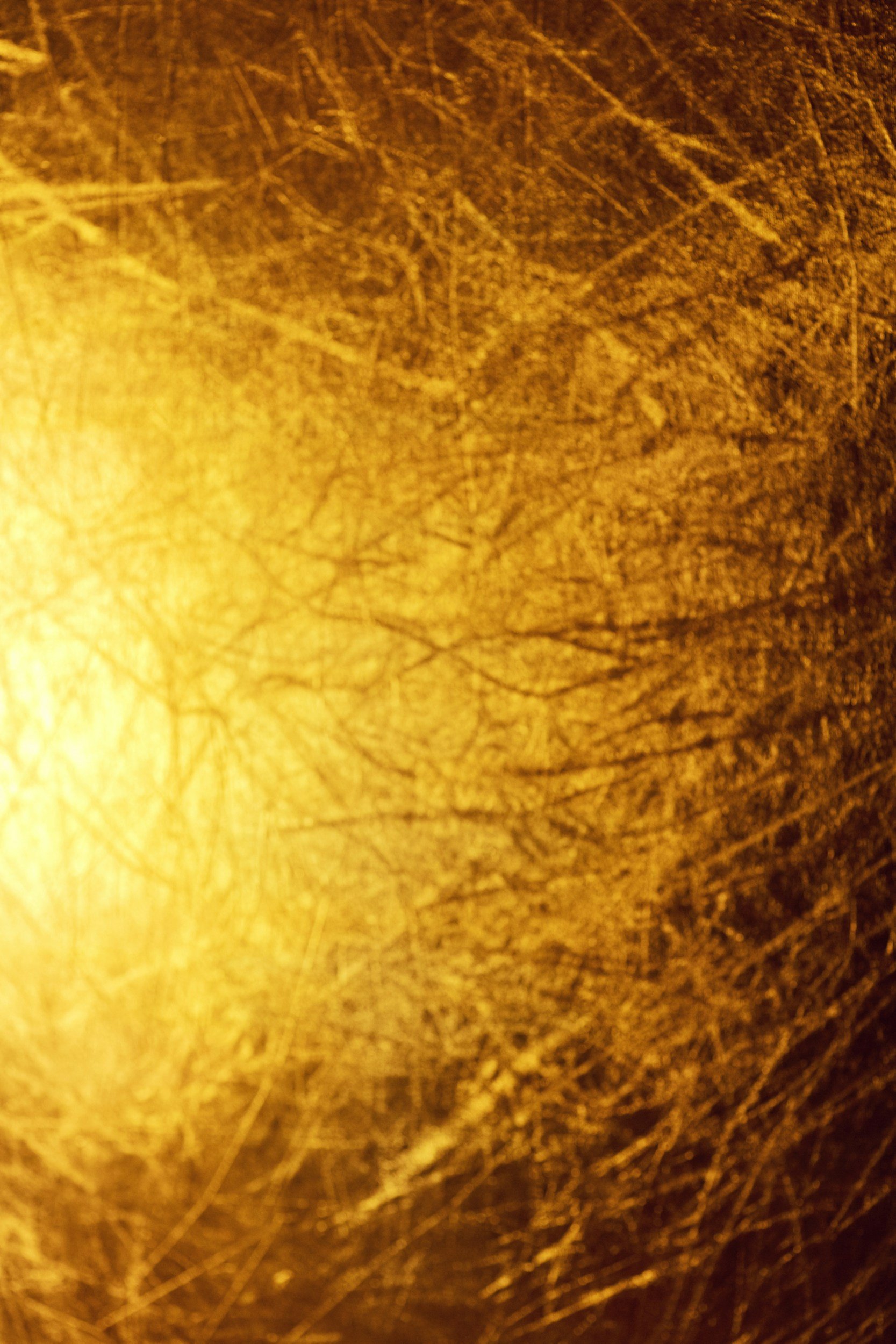 Close-up of a textured, scratched golden surface with irregular lines and marks.