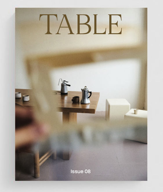 A magazine cover titled 'TABLE' with a blurred view of a table set with coffee pots and cups, seen through a wooden frame, and 'Issue 08' written at the bottom.