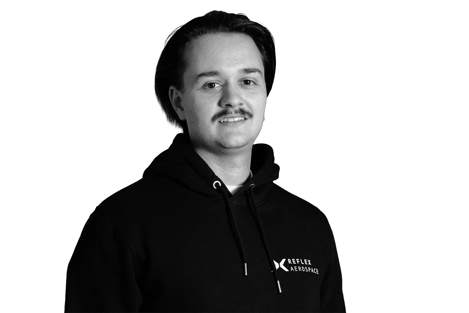 Black-and-white portrait of Dimitrie Jbanca, Bid Manager at Reflex Aerospace, with dark hair and a mustache, wearing a black hoodie with the logo 'Reflex Aerospace'.