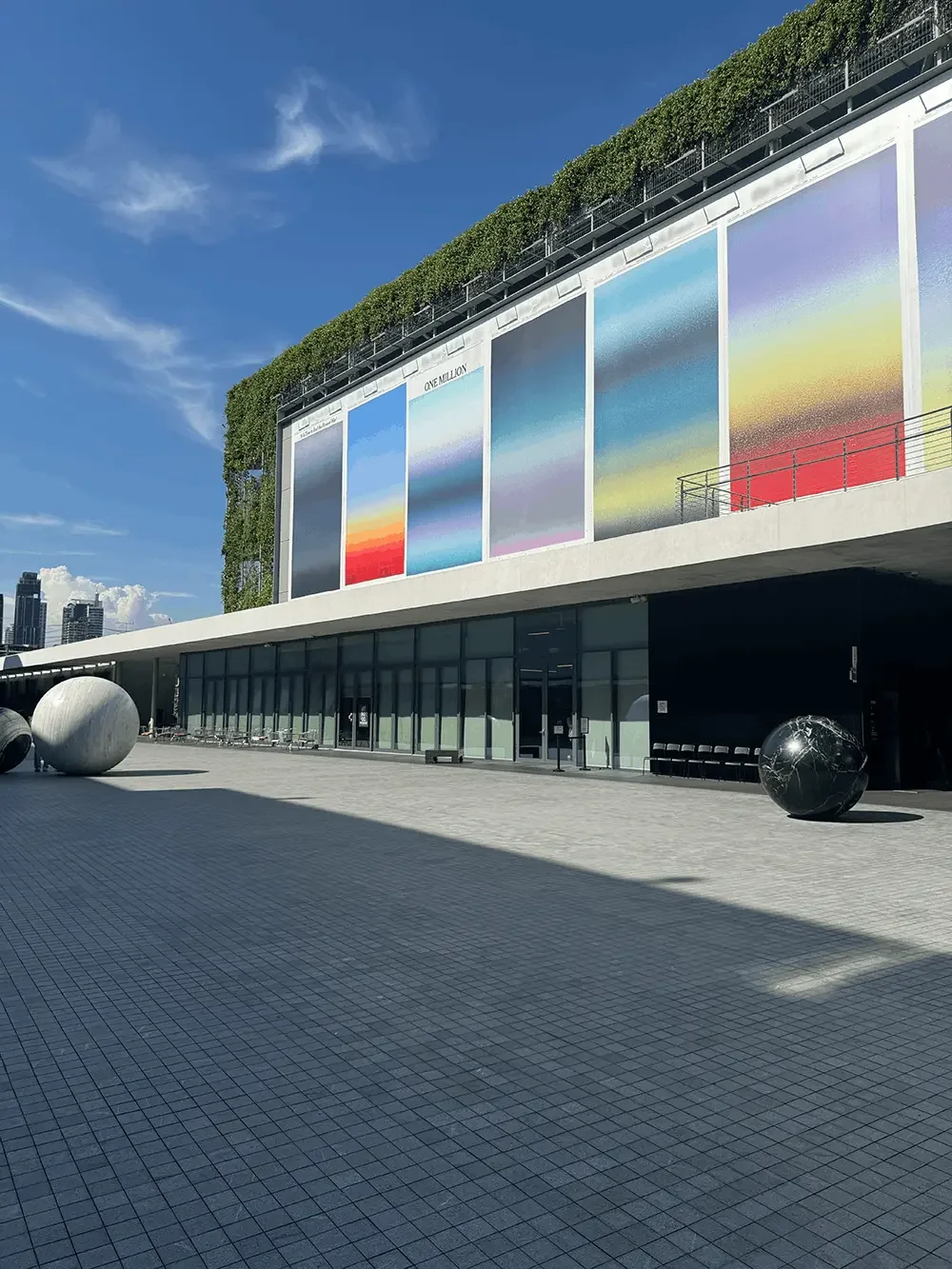 Memory mural by Sho Shibuya on the exterior facade of Dib Bangkok, featuring colourful sunrise gradient panels above the open courtyard