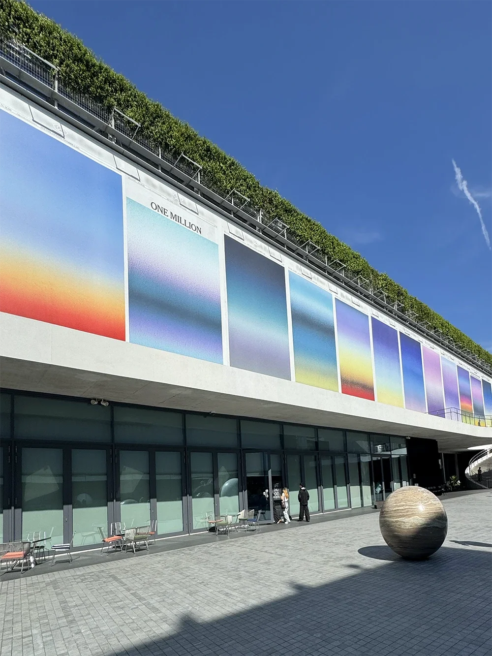 Memory mural by Sho Shibuya on the exterior facade of Dib Bangkok, featuring colourful sunrise gradient panels above the open courtyard
