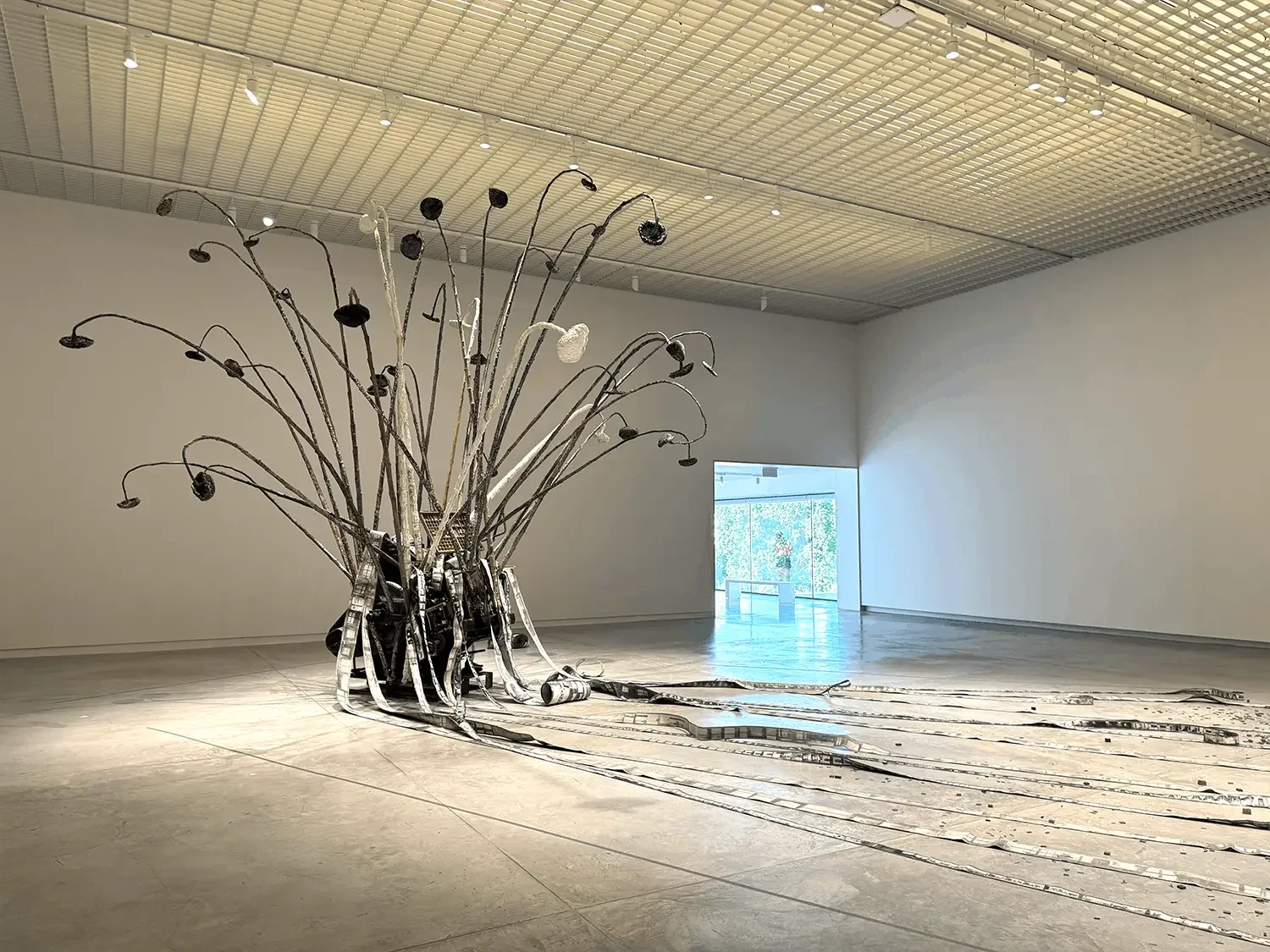 Large-scale sculptural installation in the top-floor gallery of Dib Bangkok, featuring an erupting structure of metal rods, cranes, and industrial elements spread across the white gallery floor