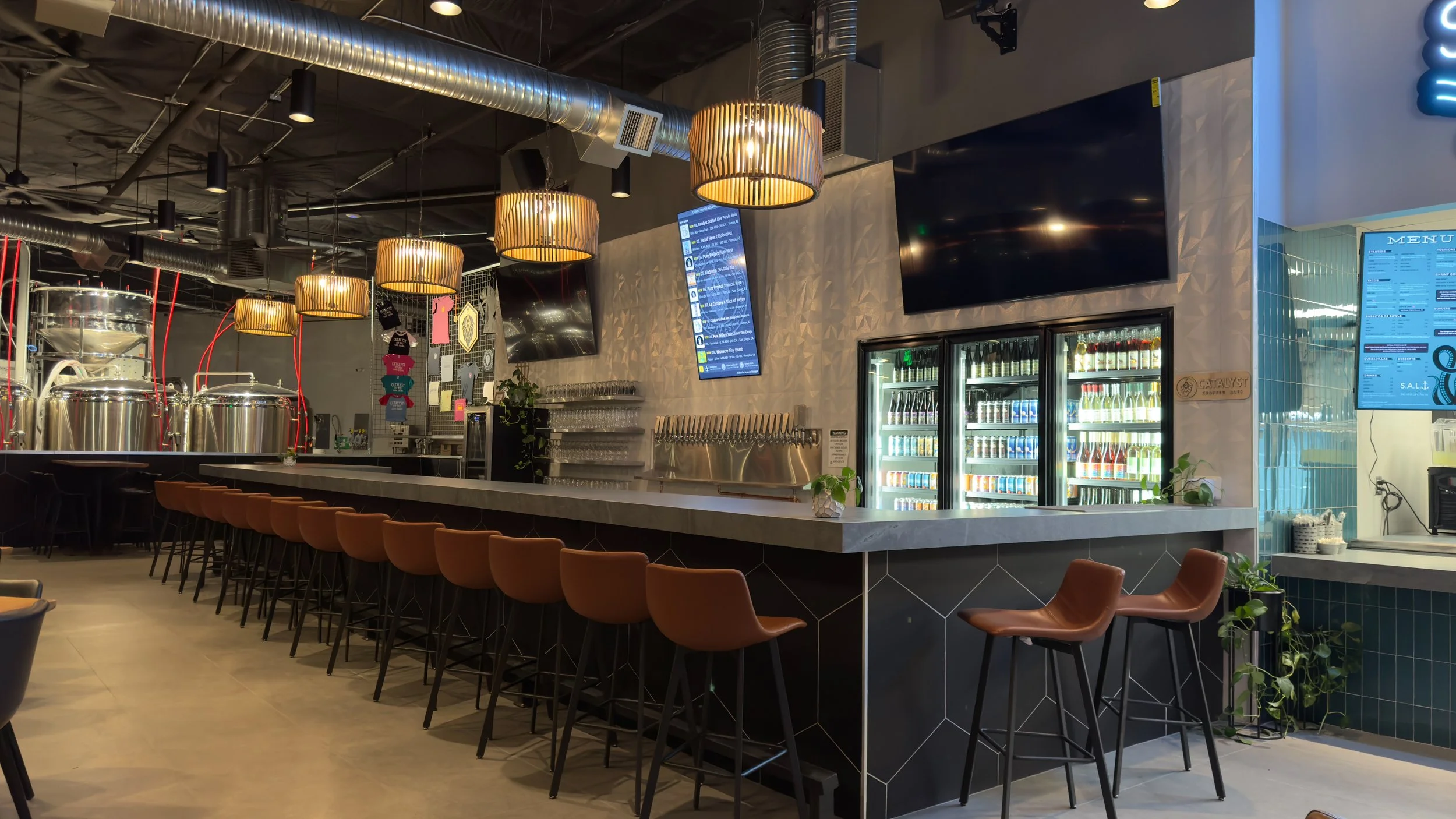 The elegant taproom of Catalyst Crafted Ales featuring metallic beer containers, and a long and neat counter top to serve beer.