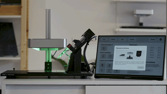 Laboratory setup with microscope, green laser, and computer screen displaying software interface.