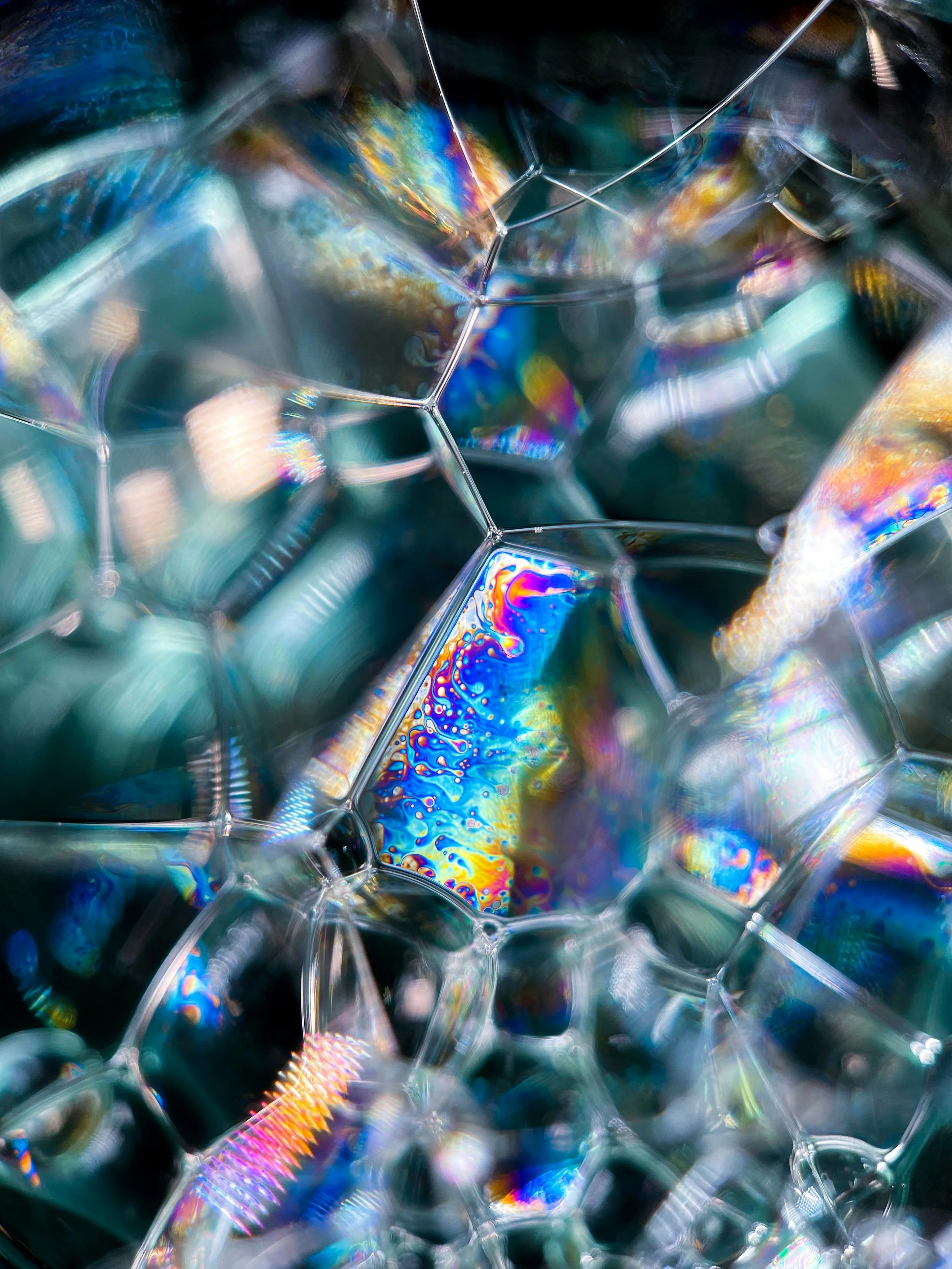 Close-up view of soap bubbles with iridescent reflections creating a colorful pattern.