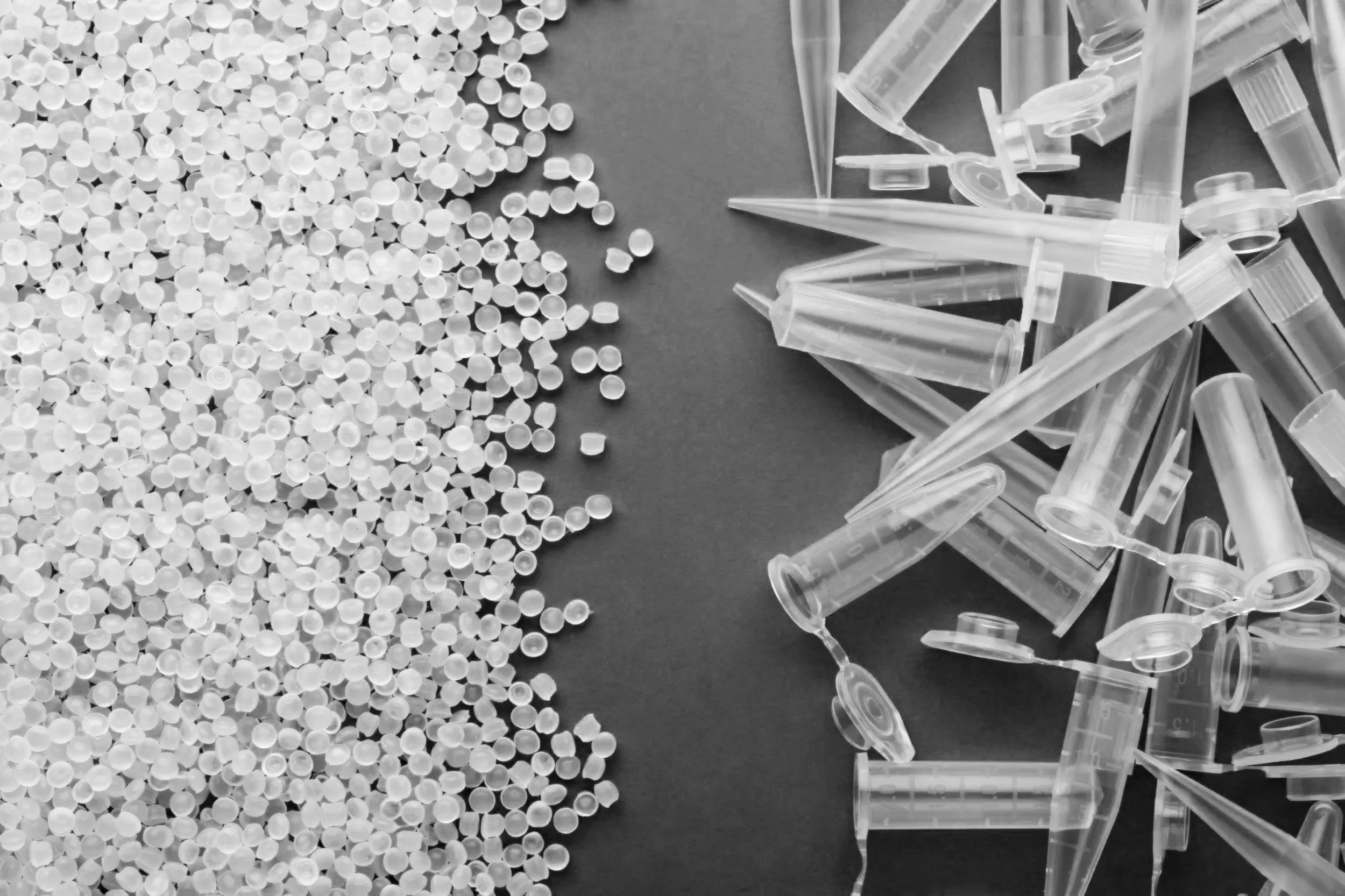 Small round white pills on the left and clear syringes with plungers on the right on a dark surface.