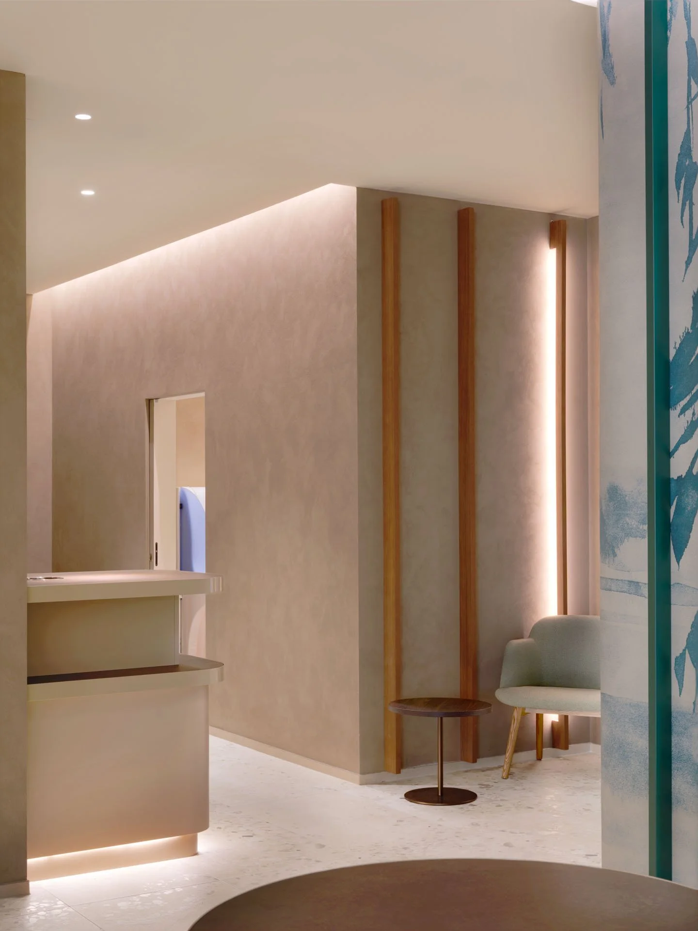 Interno con seduta, tavolino e pareti decorative in toni neutri e blu, illuminazione soffusa.