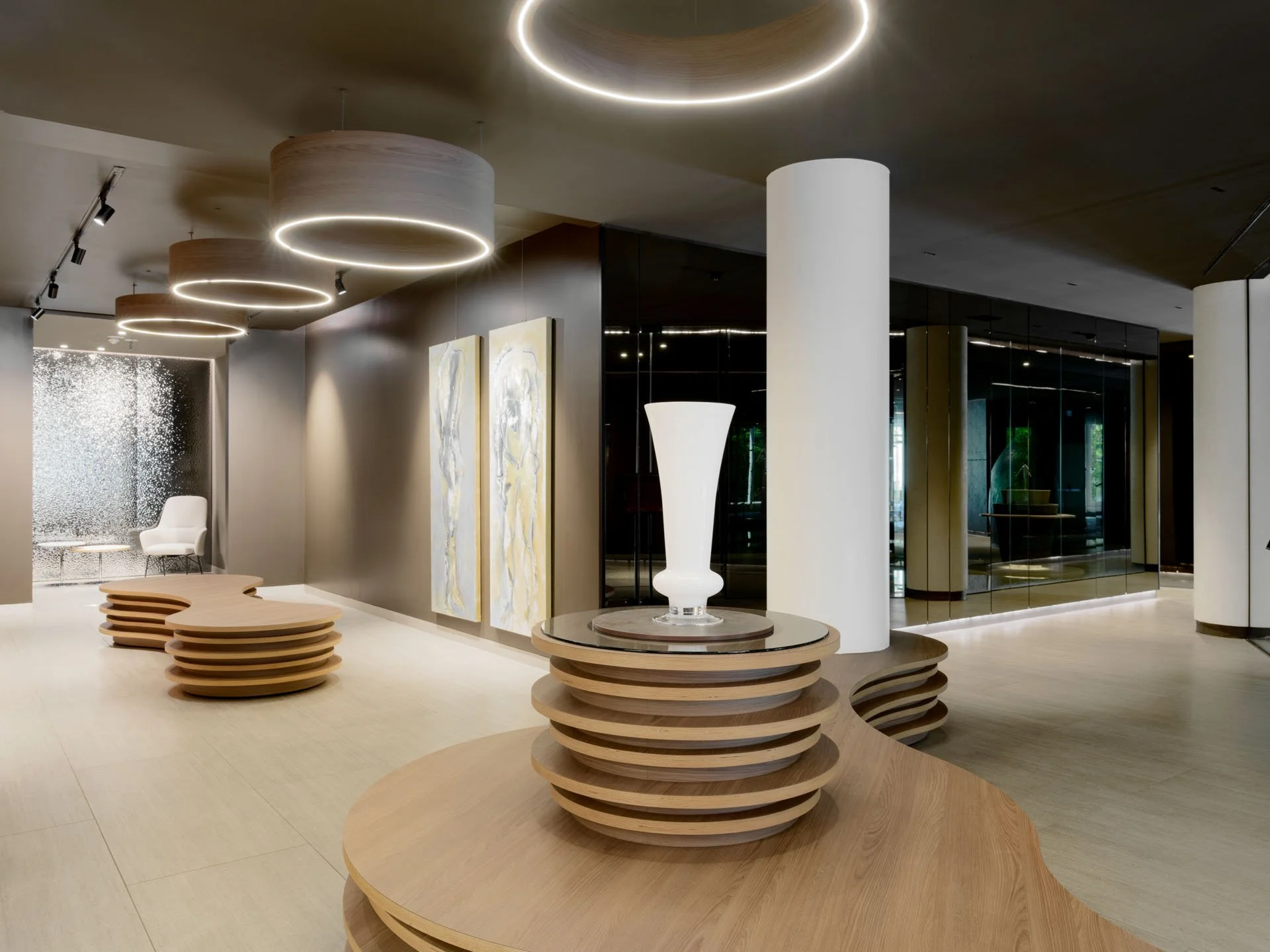 Interno moderno con luci circolari nel soffitto, sculture bianche, un tavolo con base a dischi di legno, pareti decorate con opere d'arte e pareti di vetro nero