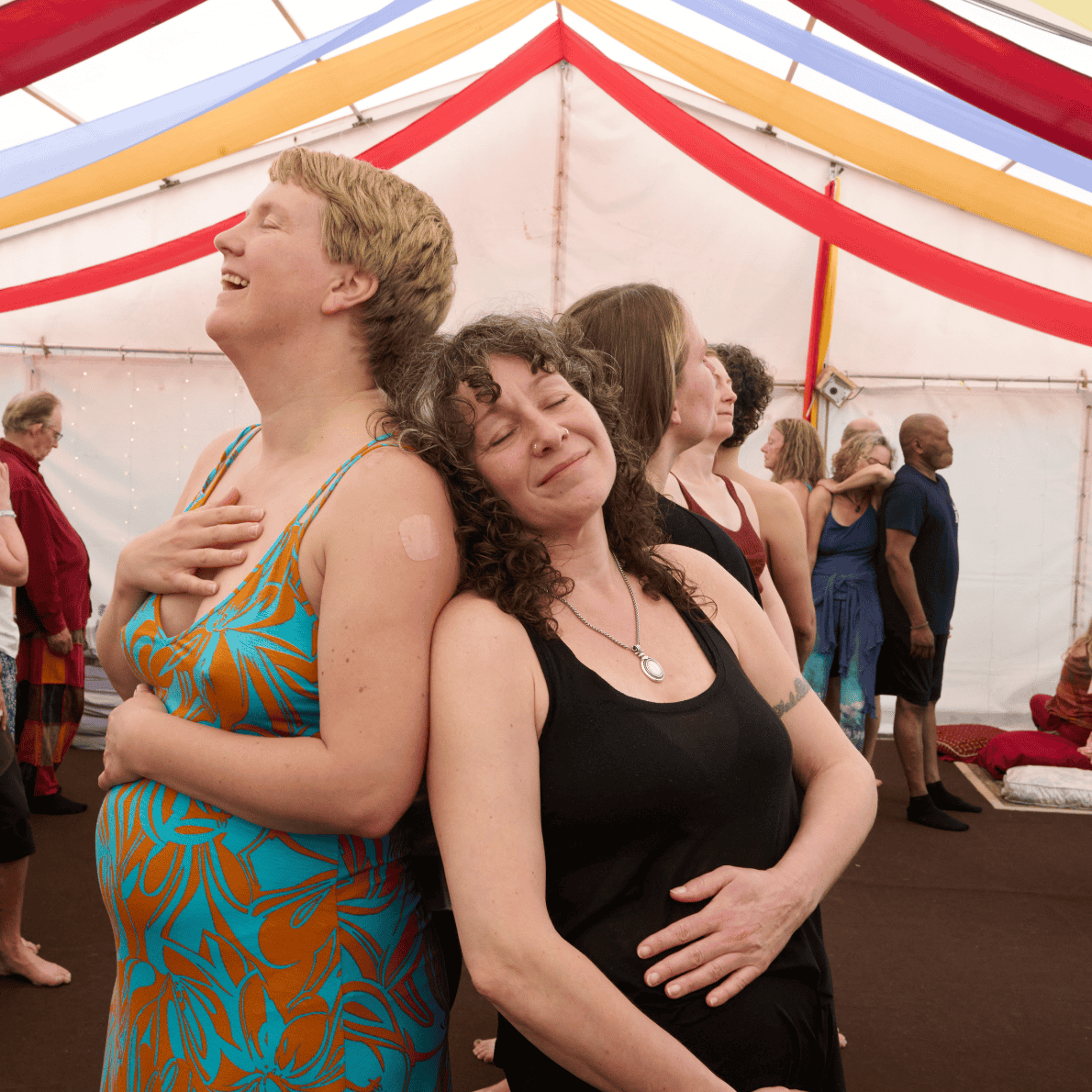People in a tent practicing yoga or meditation, standing in a heart shape with their eyes closed and hands placed on their chests or stomachs, feeling peaceful and connected.