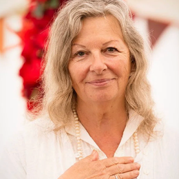 A woman with shoulder-length gray hair, wearing a white blouse and pearls.