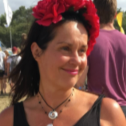 Woman wearing a red flower crown and a black top, outdoors at an event.