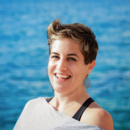 Woman with short hair smiling outdoors near the water