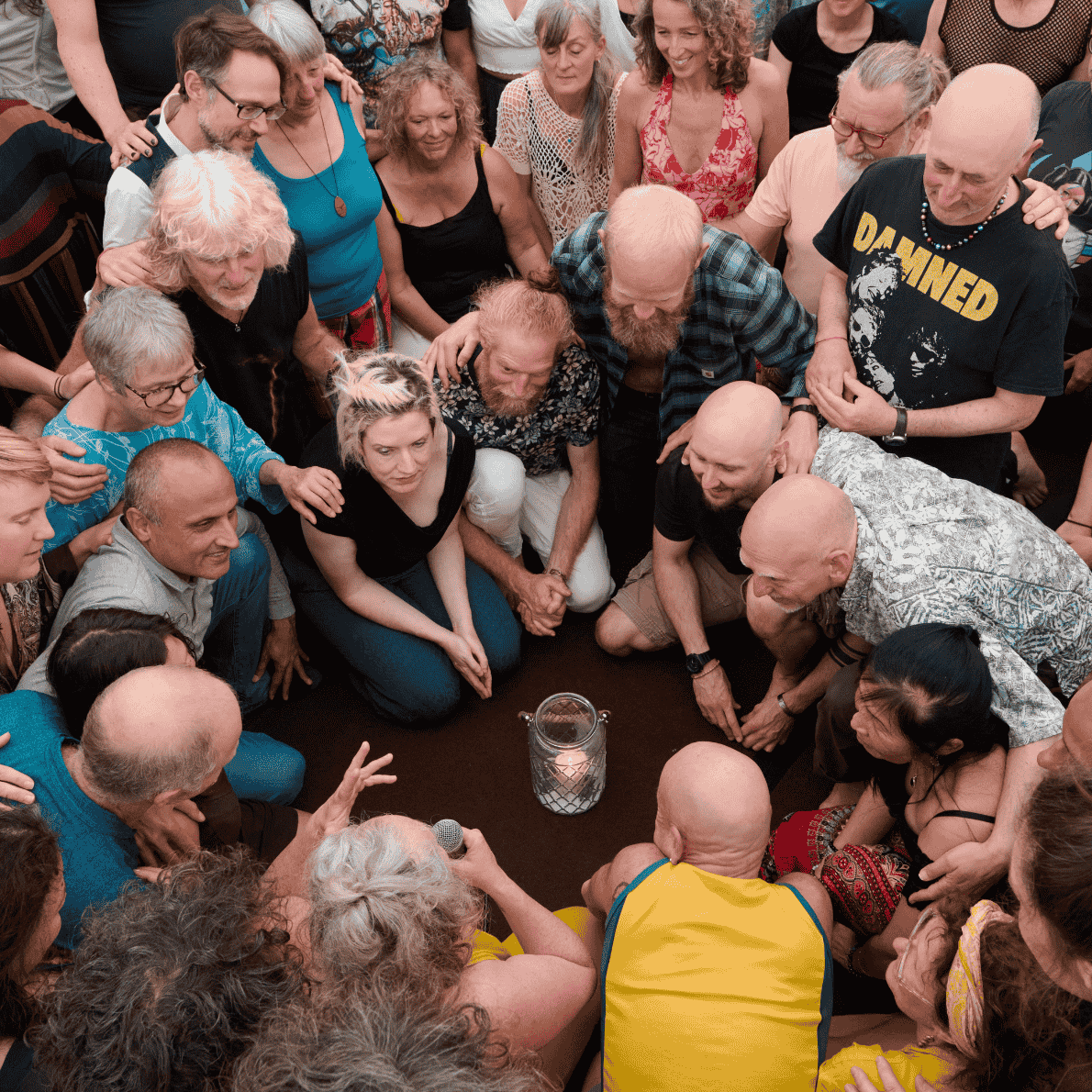 A group of people gathered in a circle around a jar with a candle inside, participating in a shared activity.