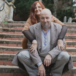 A woman and a man sitting on outdoor stairs, smiling and posing for the photo.