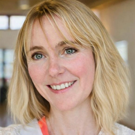 Portrait of a smiling woman with blonde hair and blue eyes.