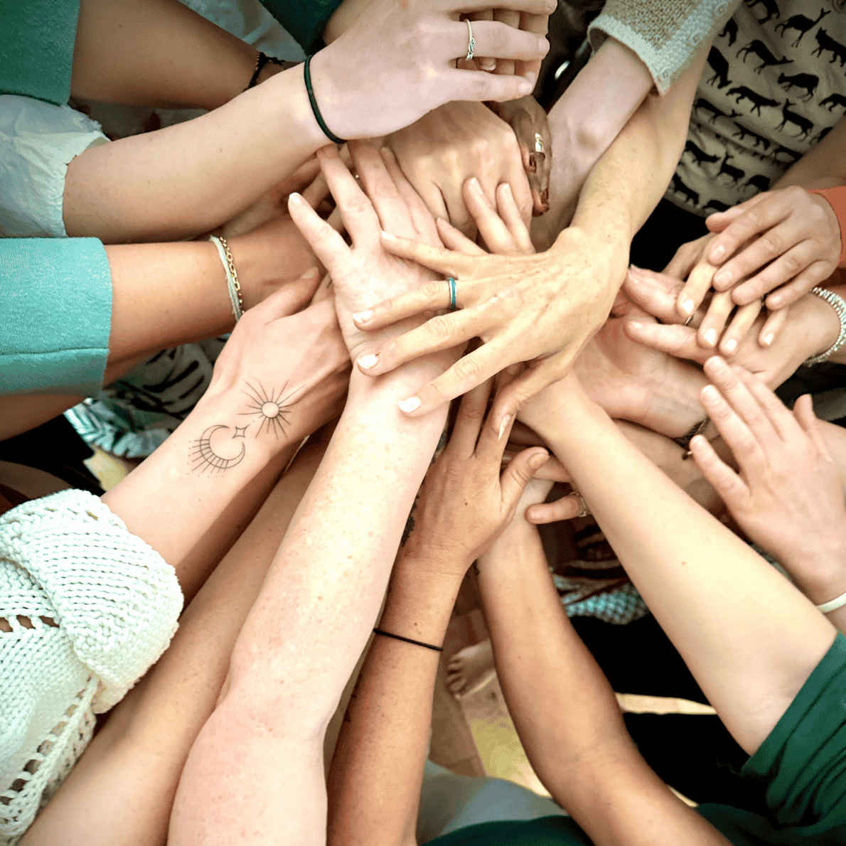 Multiple hands of diverse people stacked together in a circle, symbolizing unity and teamwork.