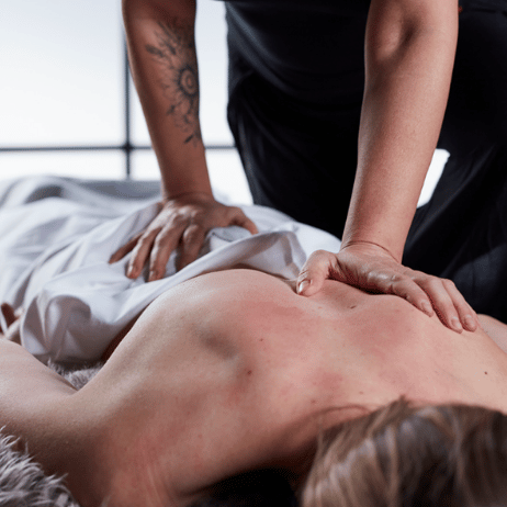 A person receiving a massage on their back from a massage therapist in a spa or wellness setting.