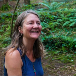 Woman smiling outdoors in a lush green forest