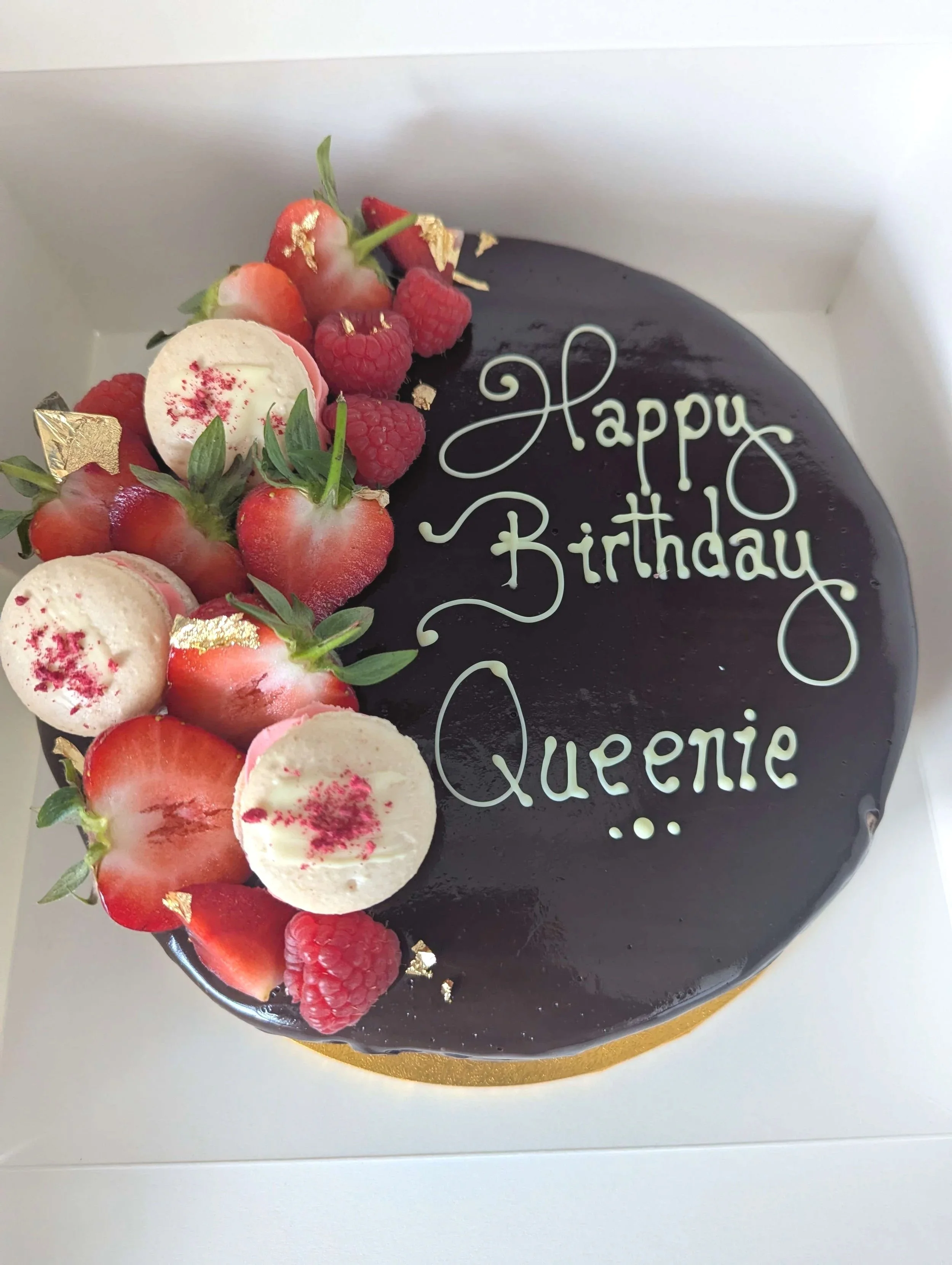 Handcrafted patisserie birthday cake with chocolate mirror glaze and fruit to one side